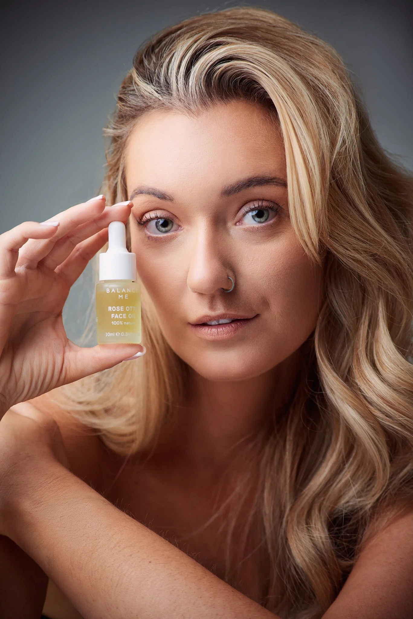 Woman applying skincare cream to her face, smiling with her eyes closed.