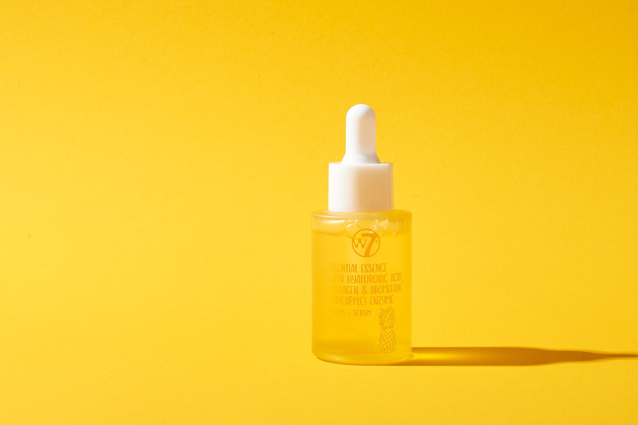 Dropper bottle with clear liquid on yellow background