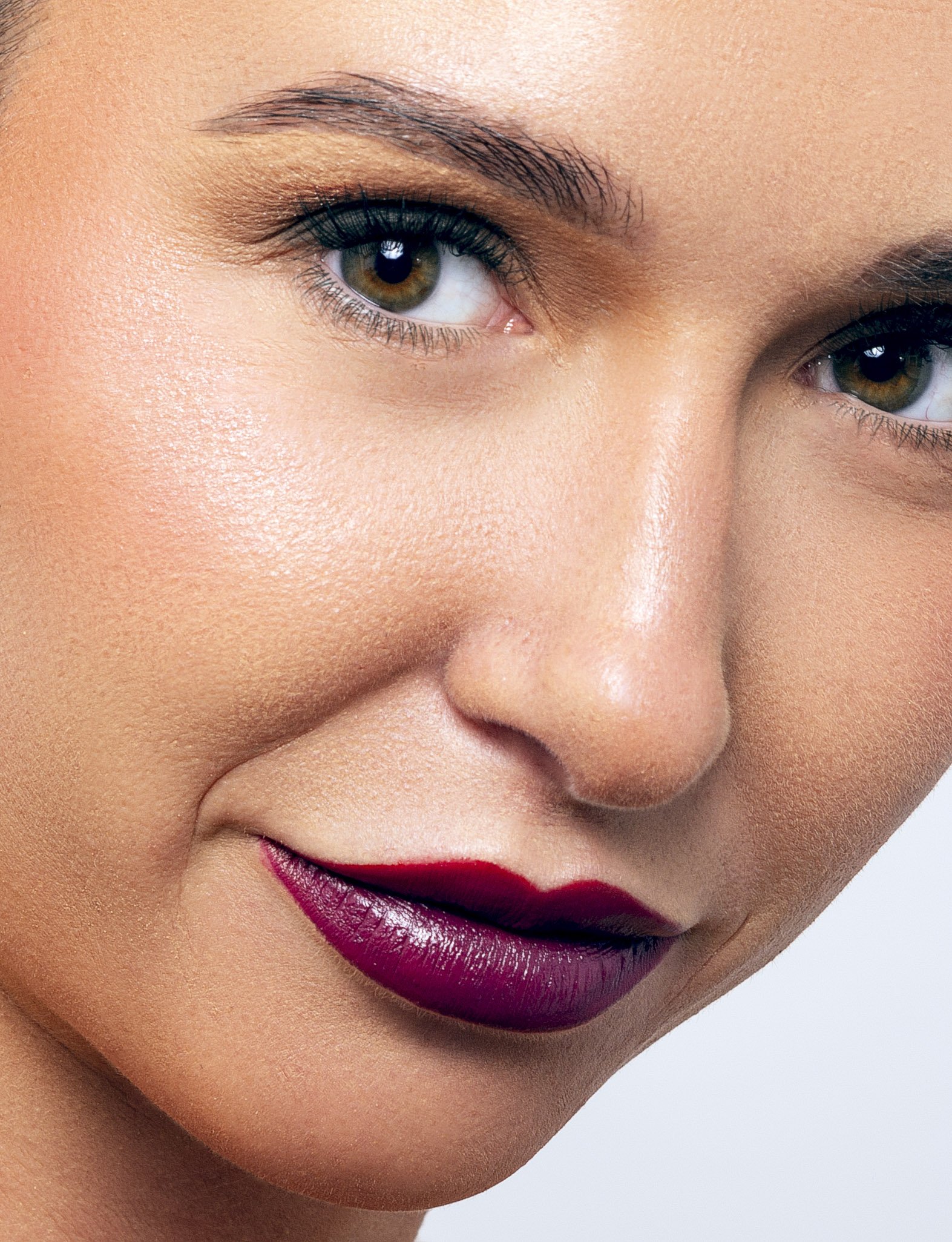 Close-up of a woman with purple lipstick and defined eyebrows