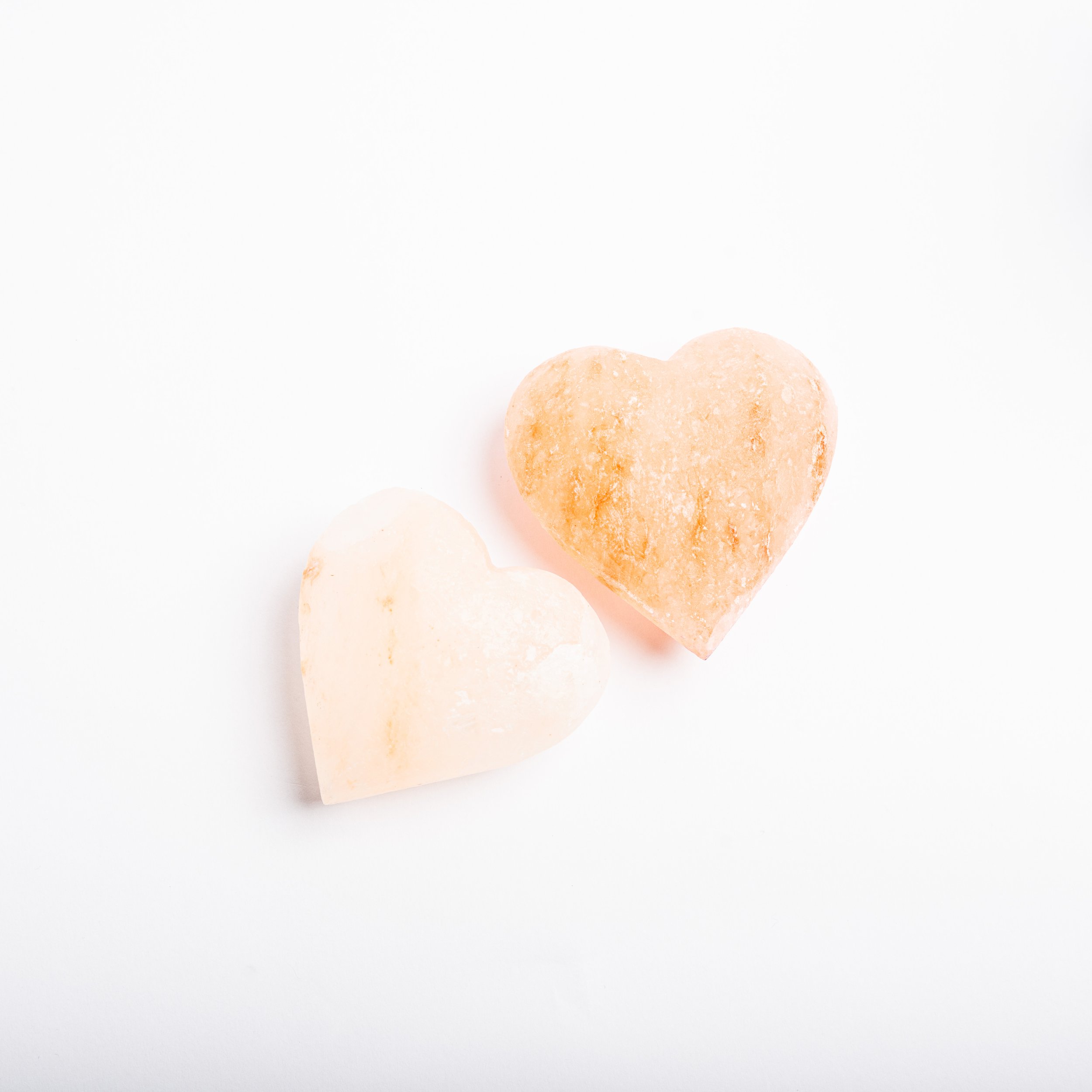 Two heart-shaped Himalayan salt stones on a white background.
