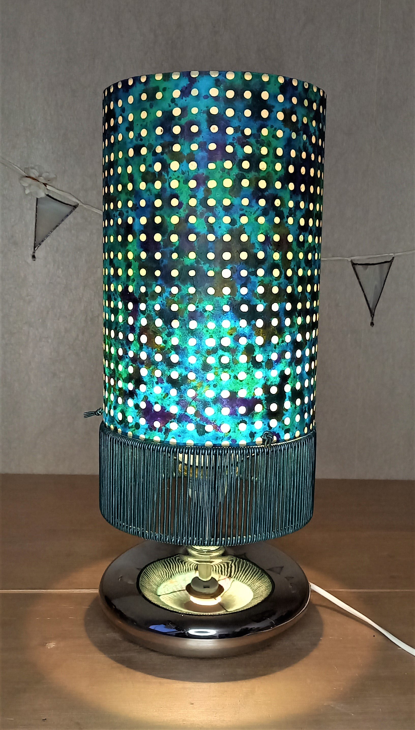 Lampe dots esprit seventies. Abat jour papier népalais en partie haute et base habillée de lacets cuir turquoise métallisé.
Pied boule aplati métal. Commande réalisée pour un particulier.