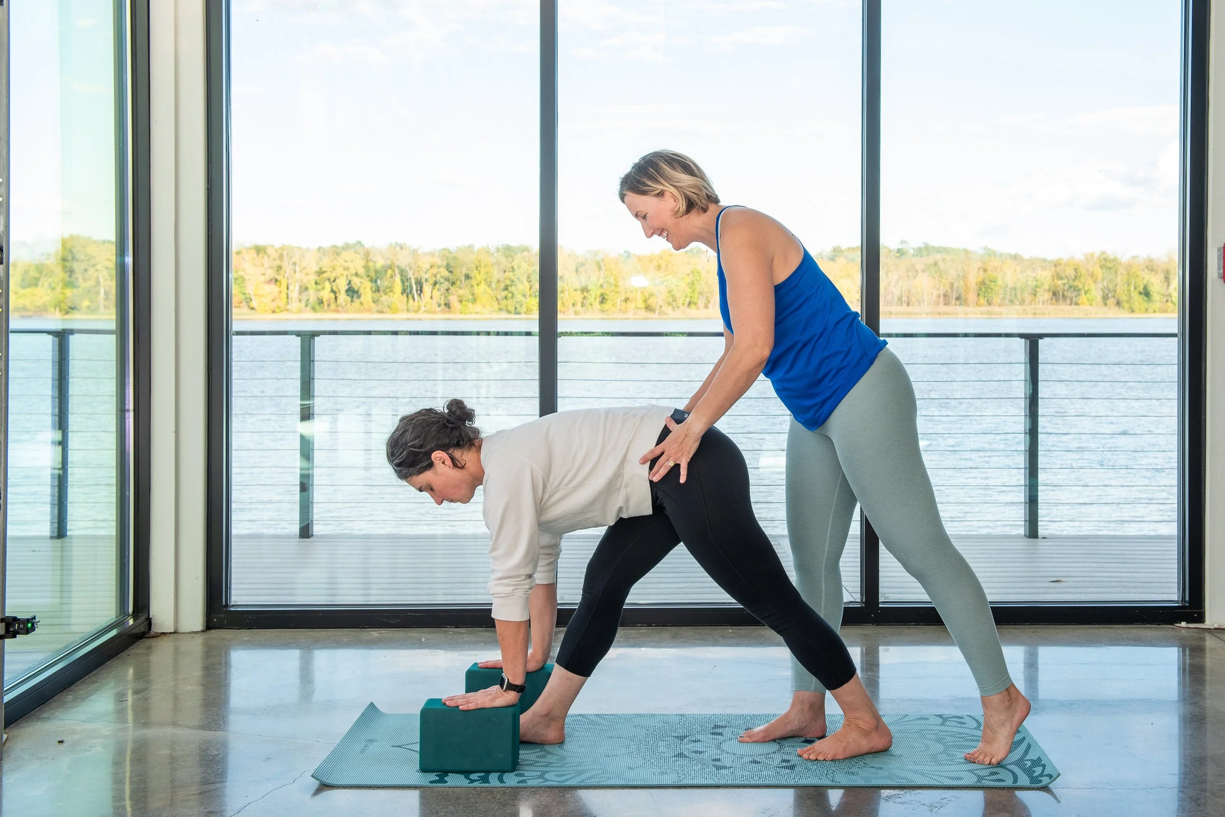 Yoga instructor Kelley Curran offering supportive guidance to a student during an in-person yoga class in Greene County, NY