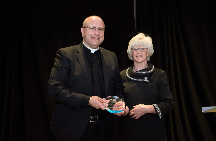 Father John Manno accepts Road to Emmaus Ministry Award from Executive Director Sheila Austin.