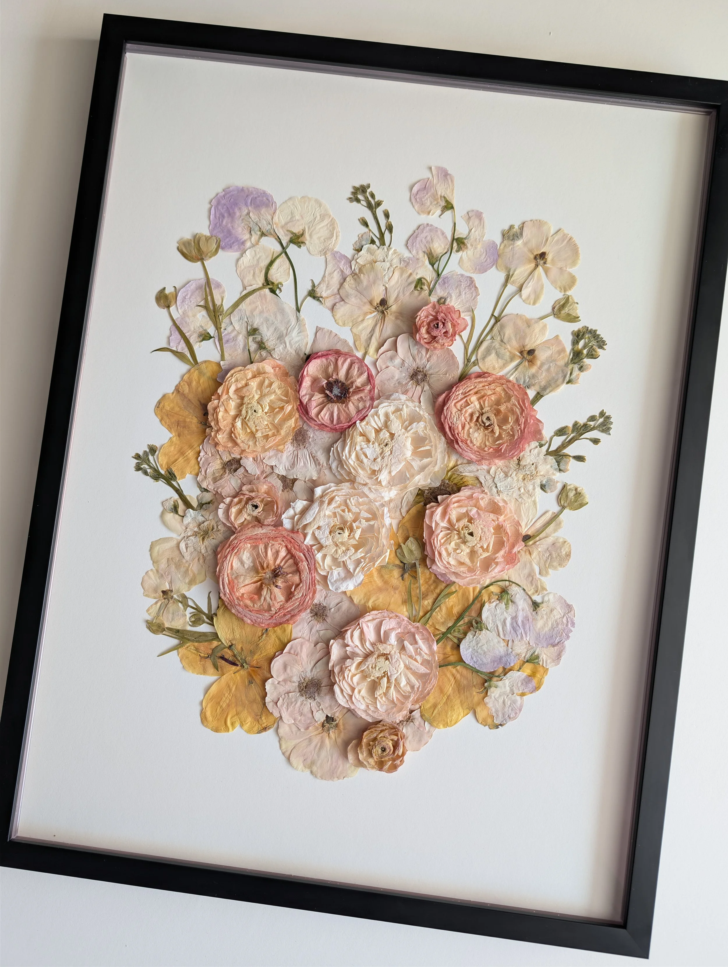 Pressed bridal flower frame featuring pastel flowers and a modern black frame.