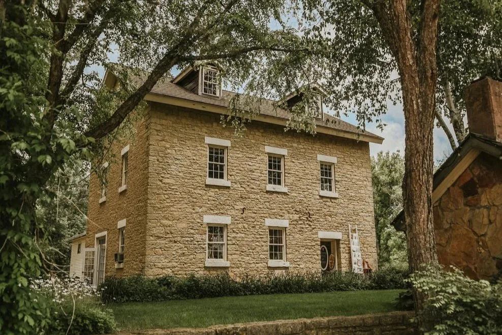 Historic stone house with trees and greenery