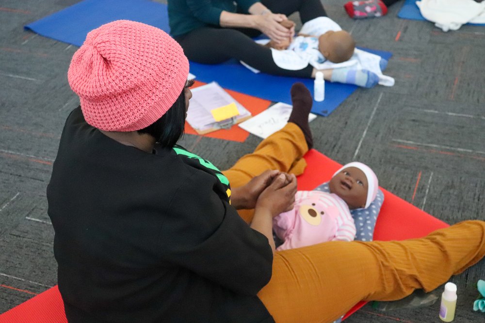 Ms. Sharon demonstrating infant massage techniques on the practice infant doll 