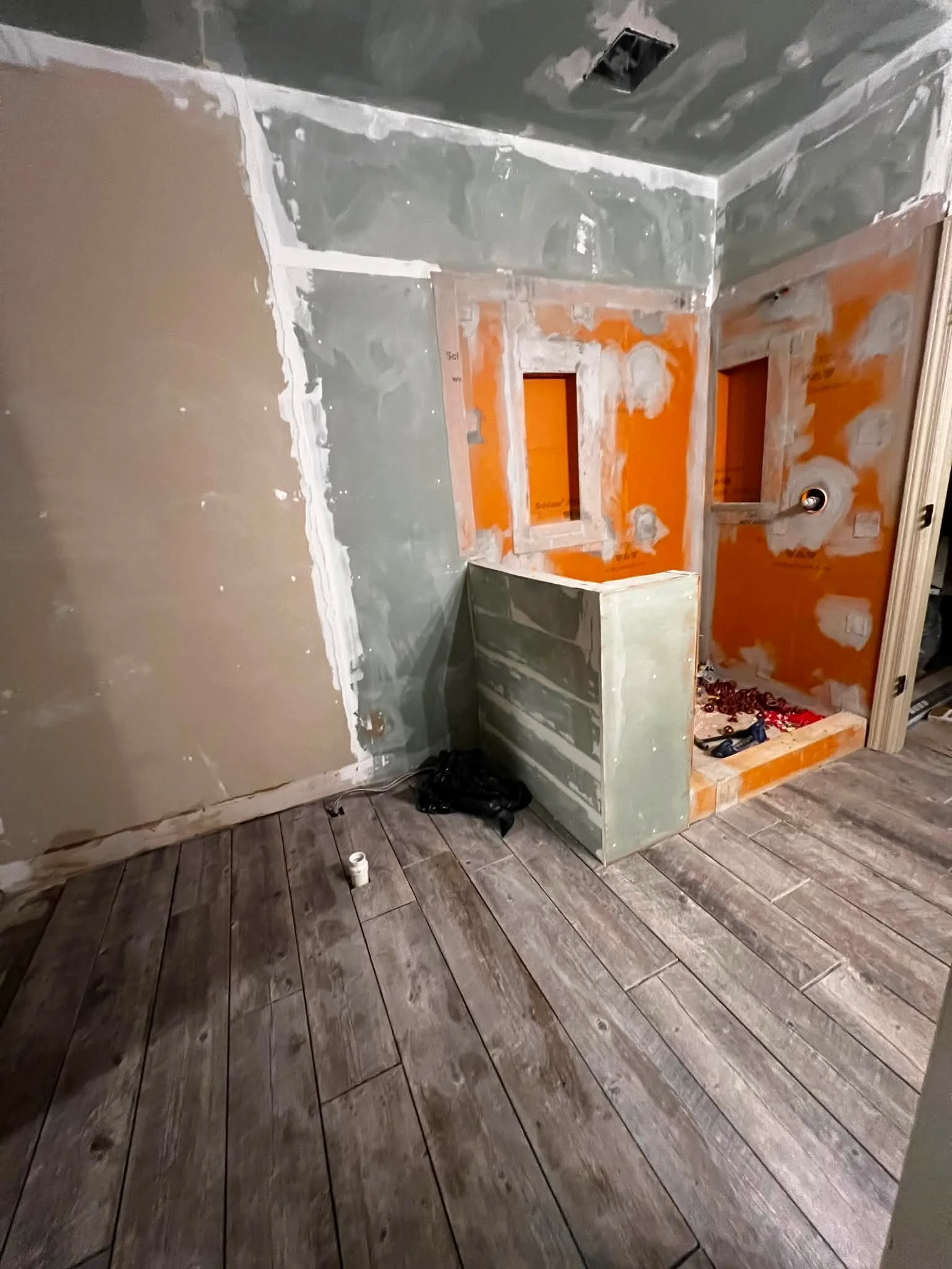 Room under construction with partially painted walls, unpainted window frame, and wooden plank floor.