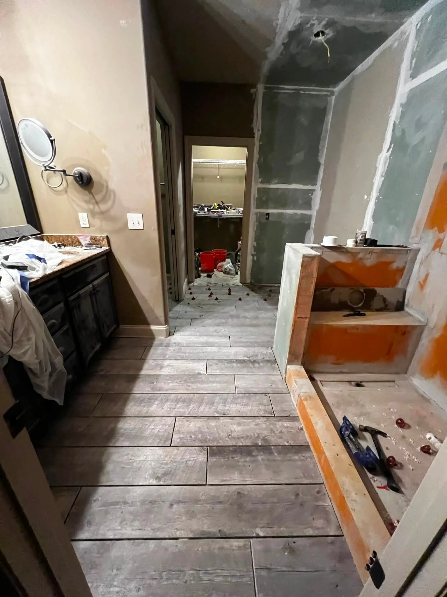Interior of a kitchen under renovation, with unfinished walls, tools, and construction materials visible, and a partially built countertop on the right.