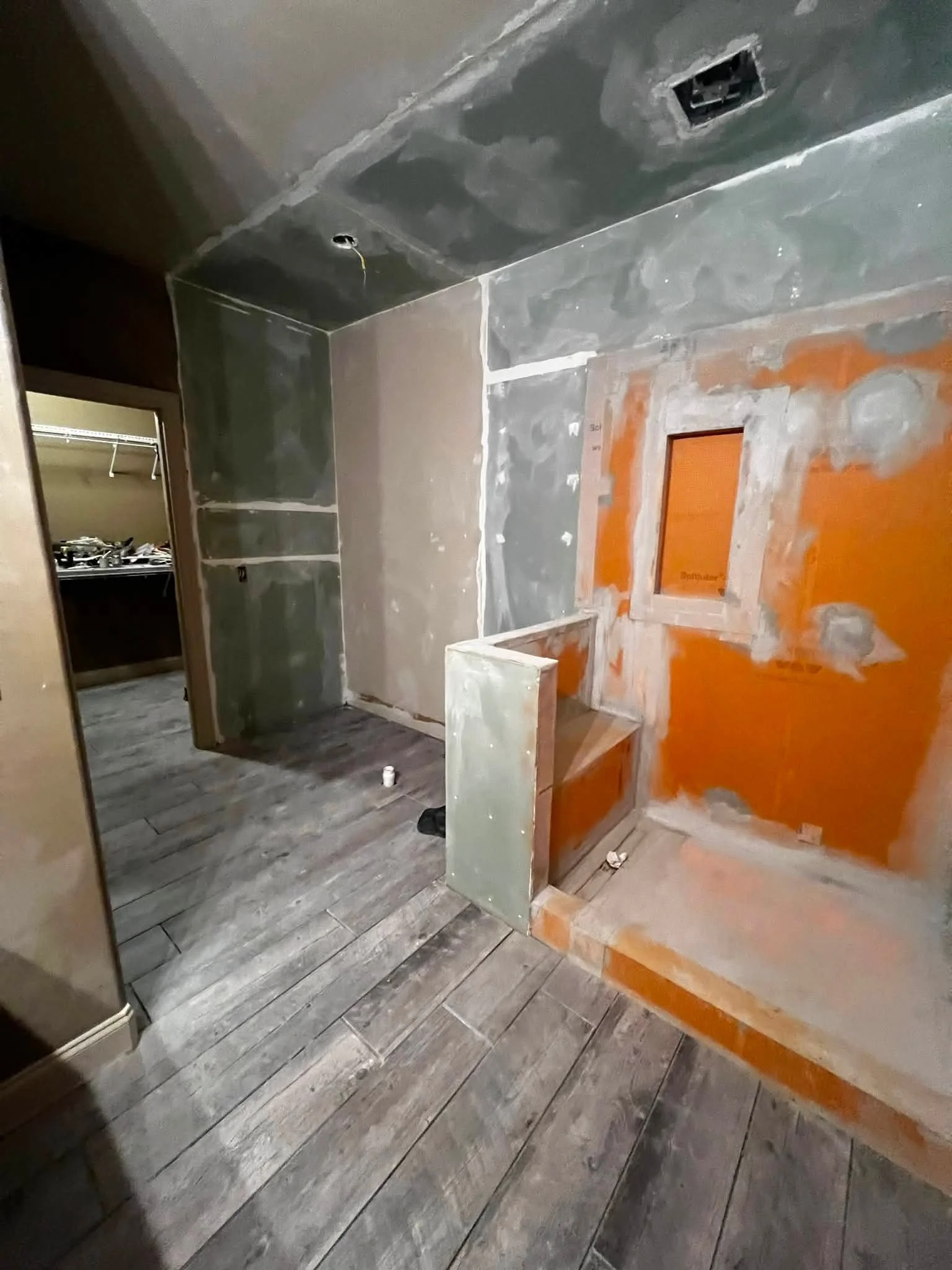 Room under construction with unfinished walls and flooring, peeling paint, and exposed openings for fixtures.