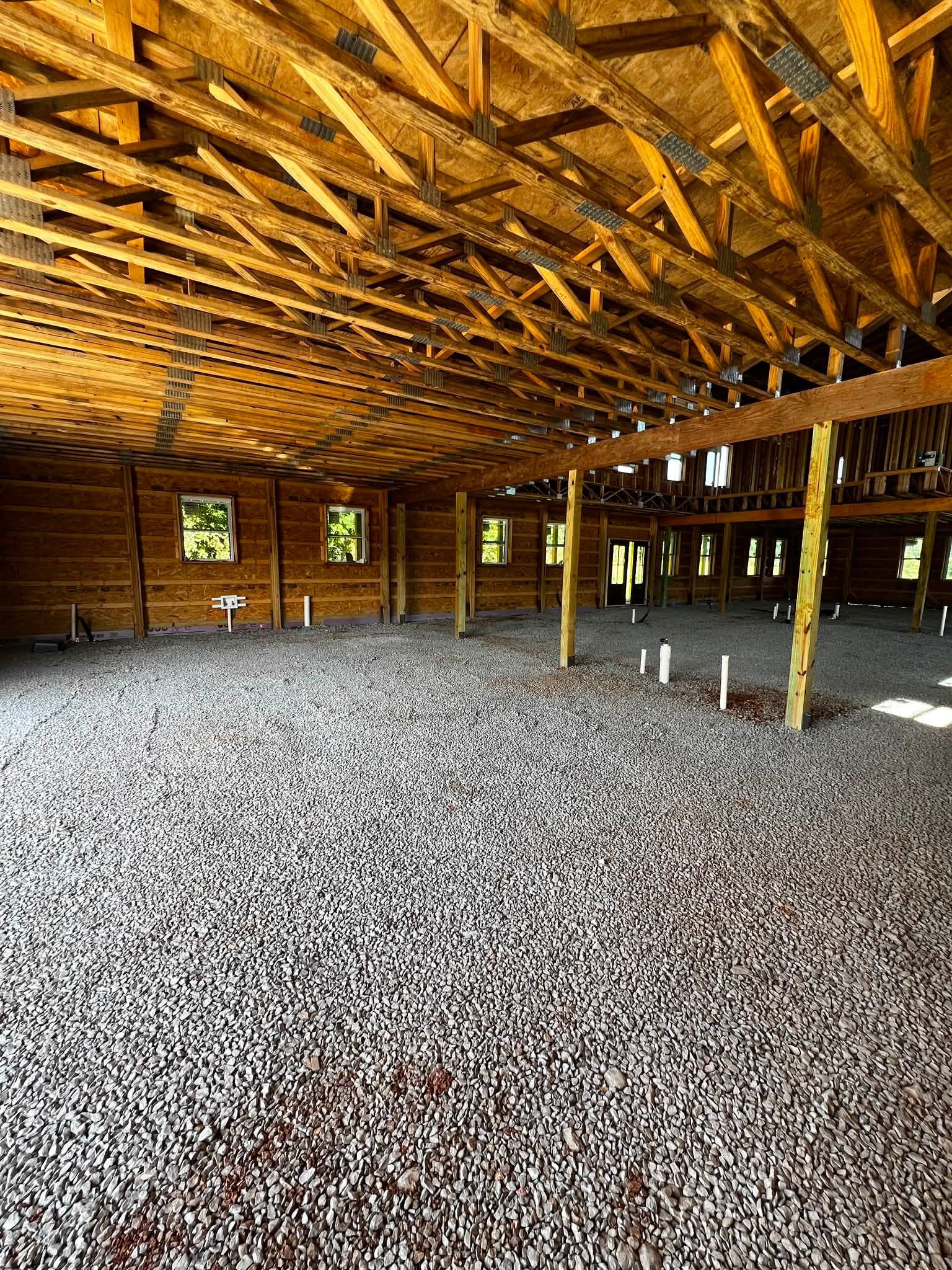 Interior of a building under construction with wooden framing and a gravel floor.