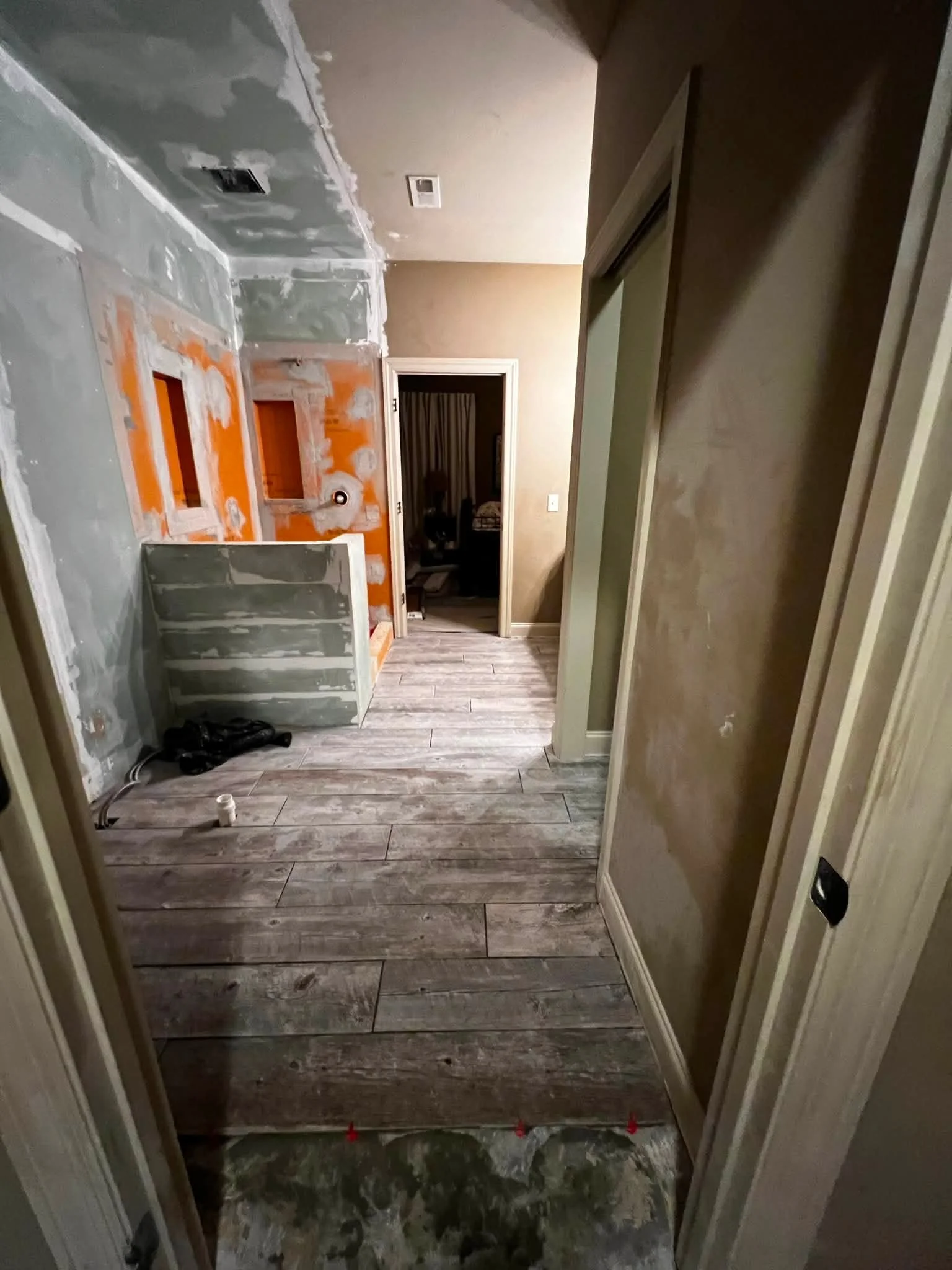 Interior of a house under renovation, showing drywall work on the walls and flooring installation in progress.