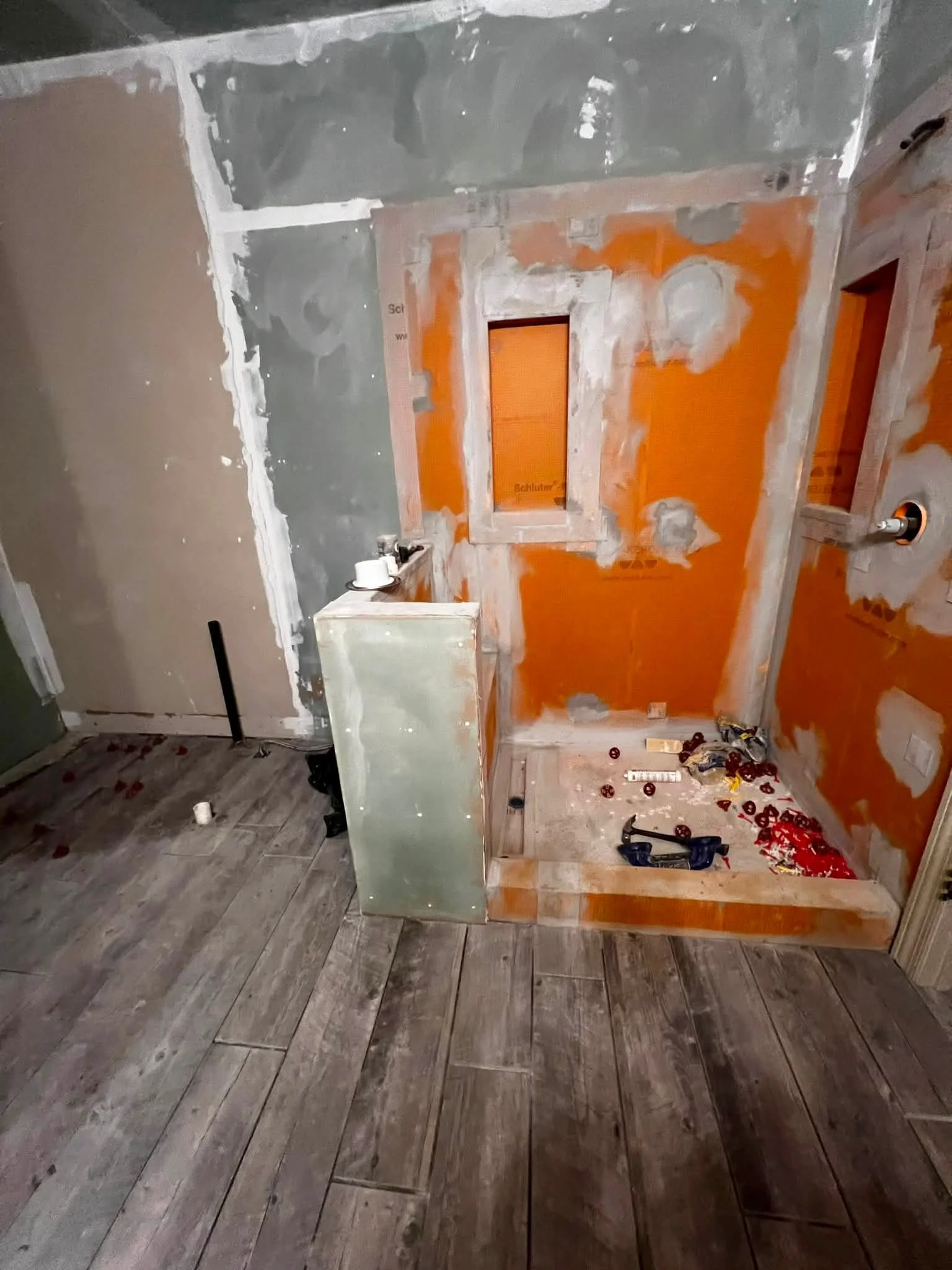Room under renovation with partially painted walls, construction tools, and wooden flooring.