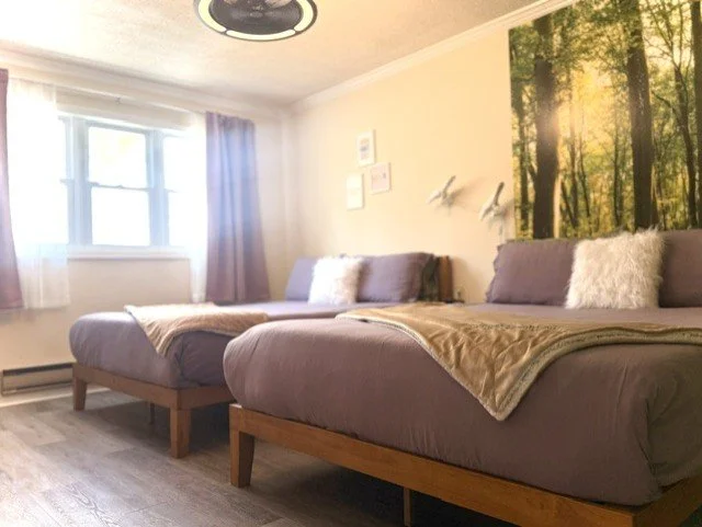 Unwind in a peaceful Catskills retreat featuring two cozy queen beds, soft four-season bedding, forest-inspired décor, and warm natural light for the perfect mountain escape.