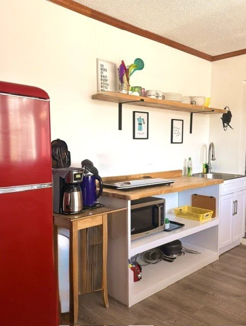 Cozy Catskills kitchenette with a retro red fridge, coffee station, dining nook, and charming cabin touches — perfect for slow mornings and relaxing mountain stays.