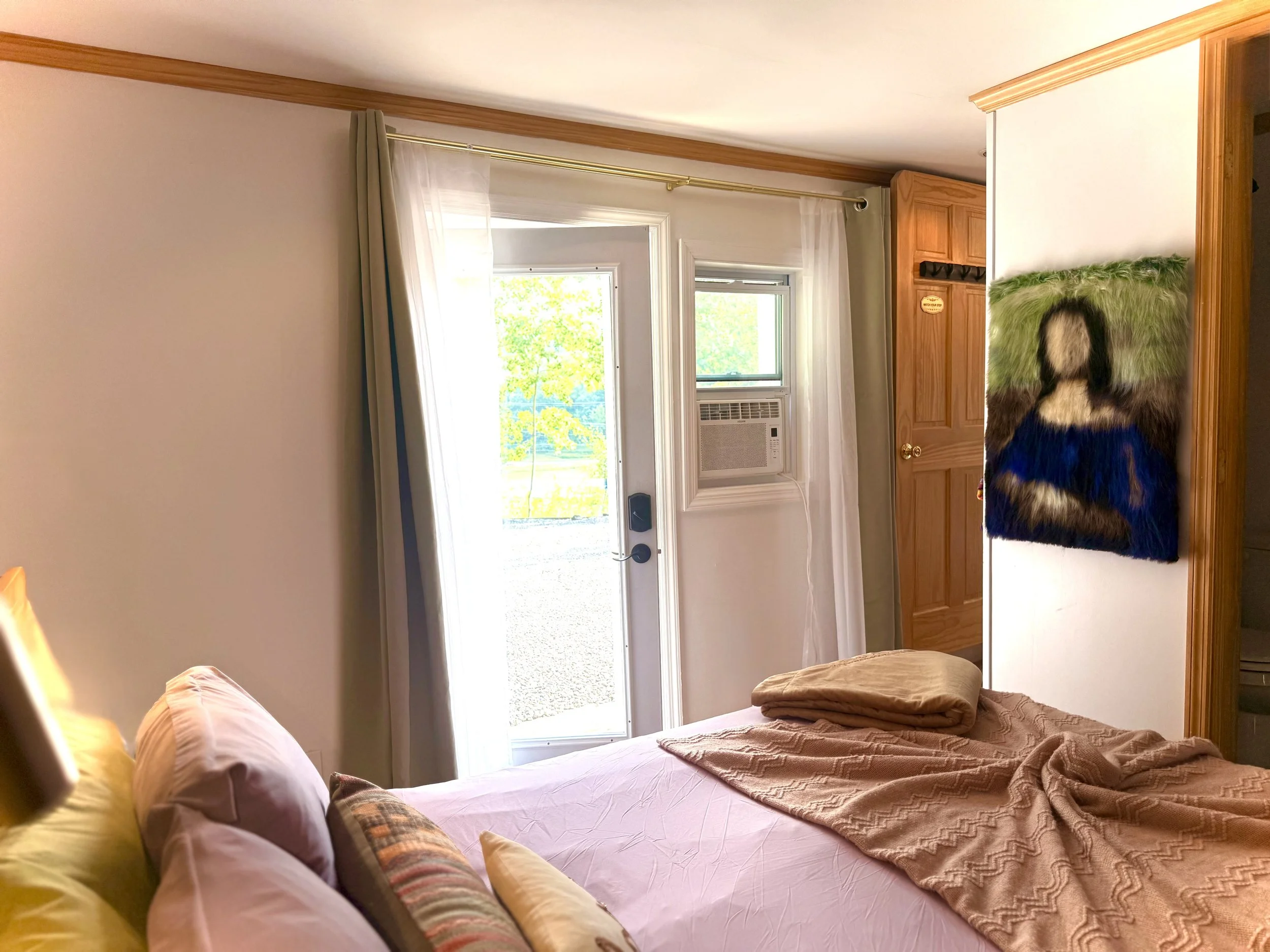 ☀️ Natural light fills this inviting bedroom at Alpine Four Season Lodge, featuring soft bedding and a glass door overlooking the properties front area. 