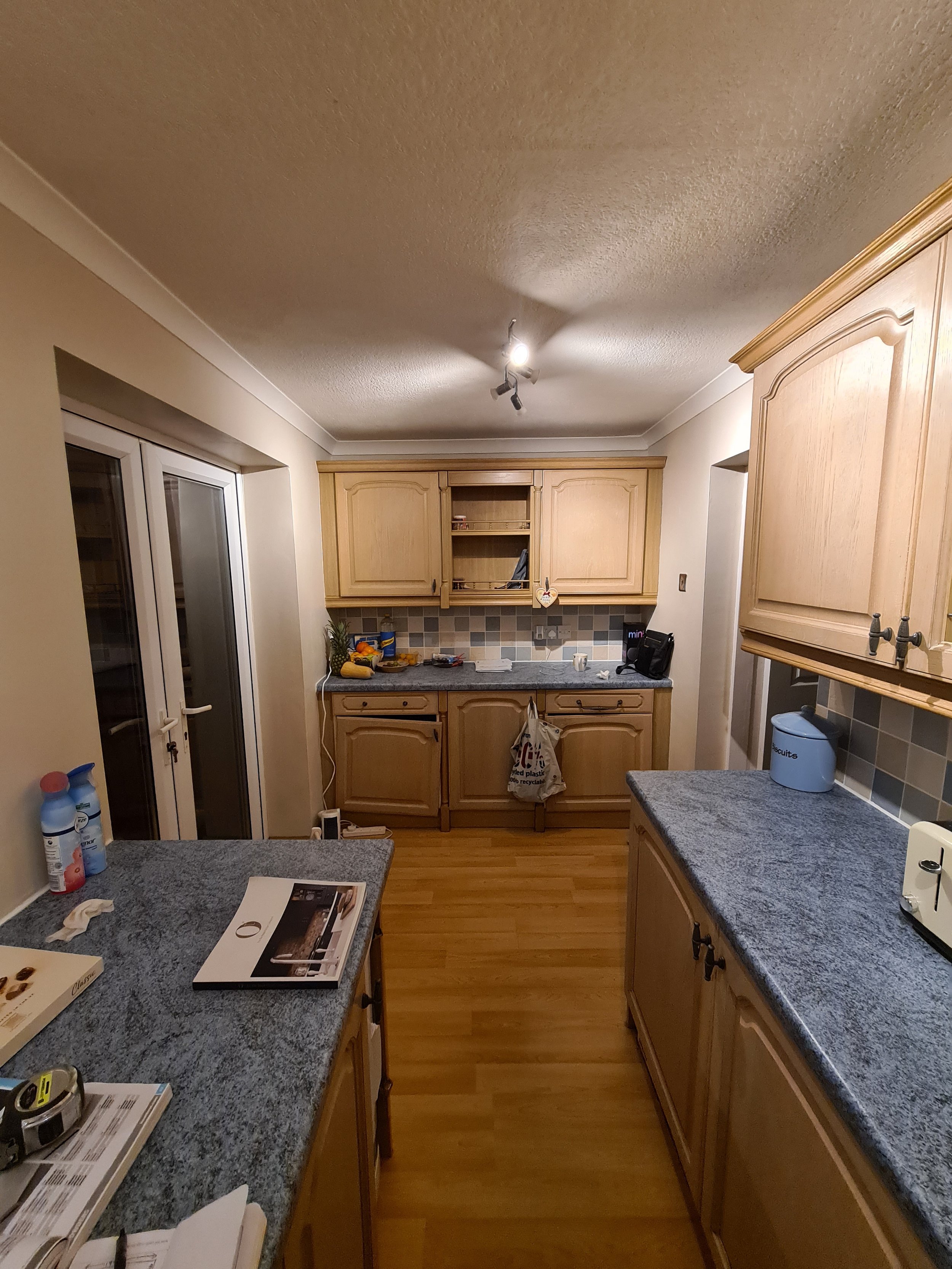 Empty kitchen with wooden cabinets, granite countertops, and a sliding glass door.