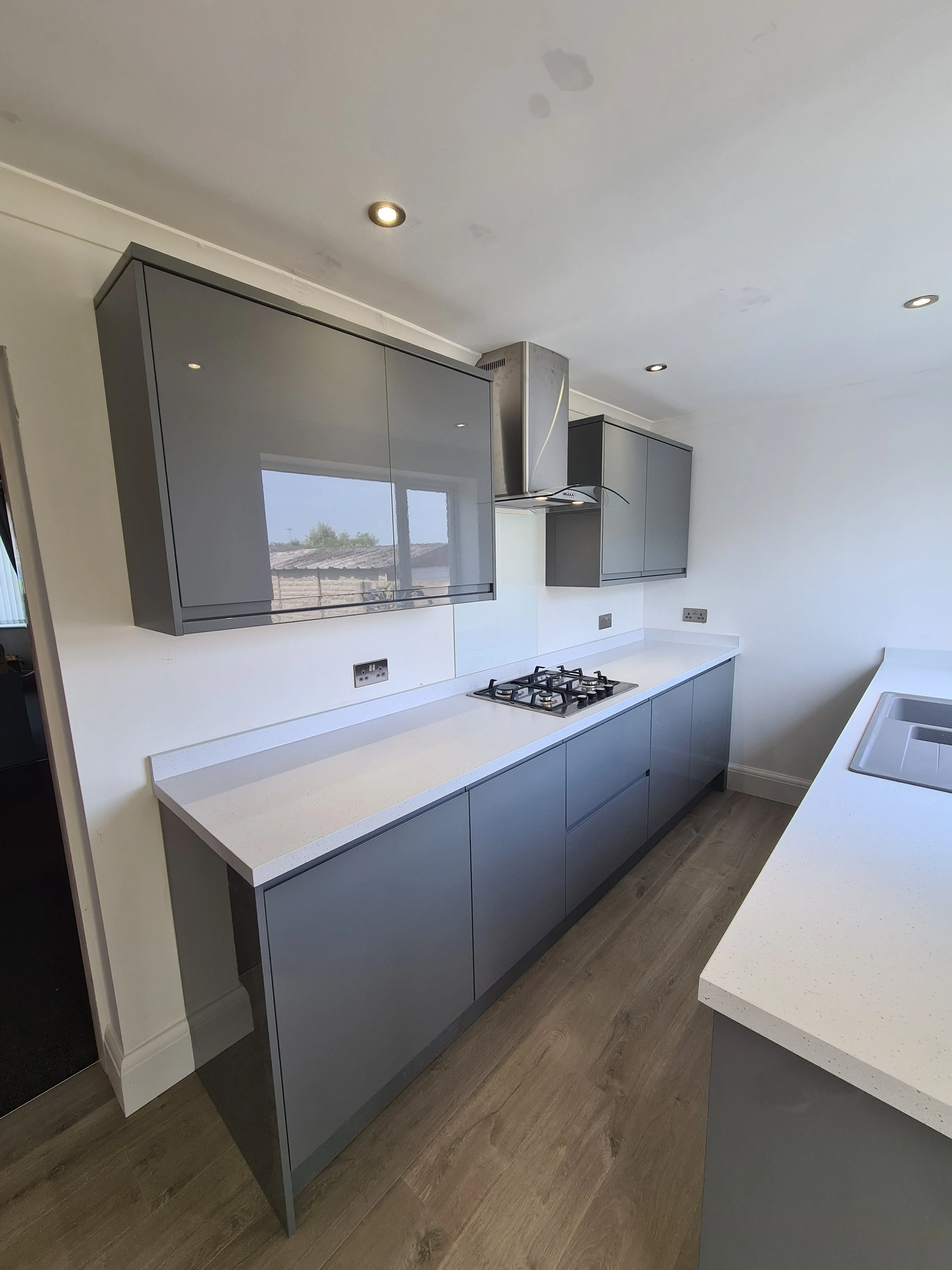 Modern kitchen with gray cabinets, white countertops, a gas stove, and a stainless steel range hood.