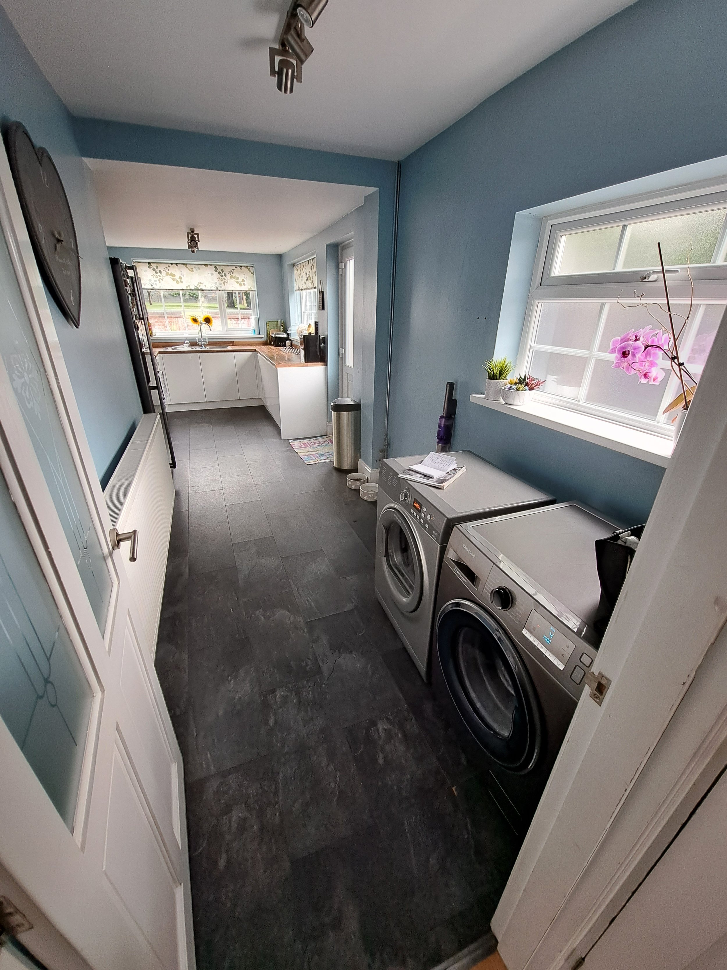 Laundry room with two front-loading washers and a window with pink orchids.