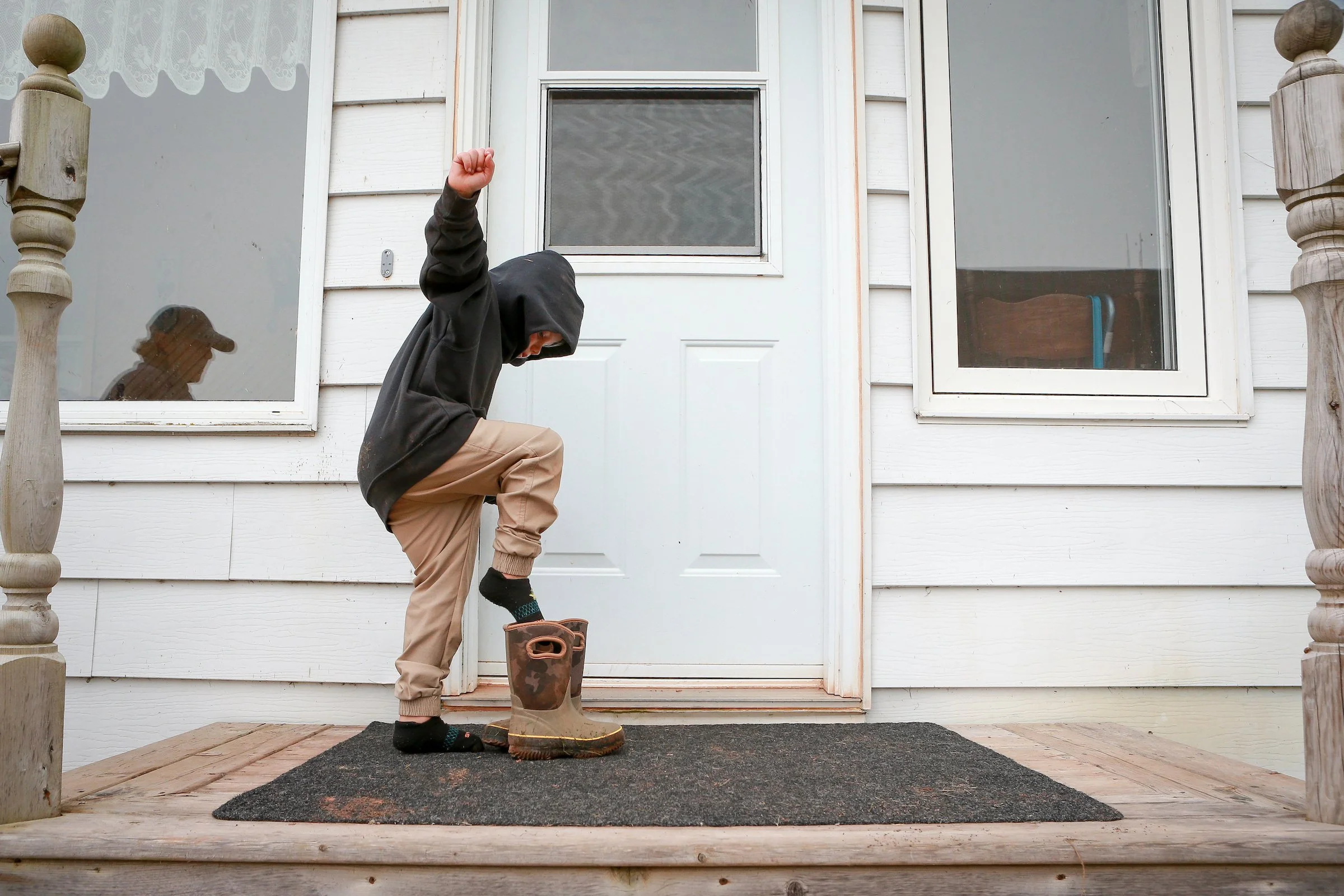 Excited to get back to helping with the farmwork, Kai at 5, steps into his boots following dinner 