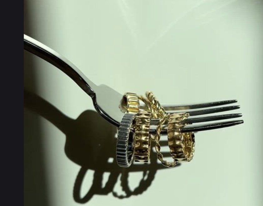 A fork holds various diamond and gold rings in shadow
