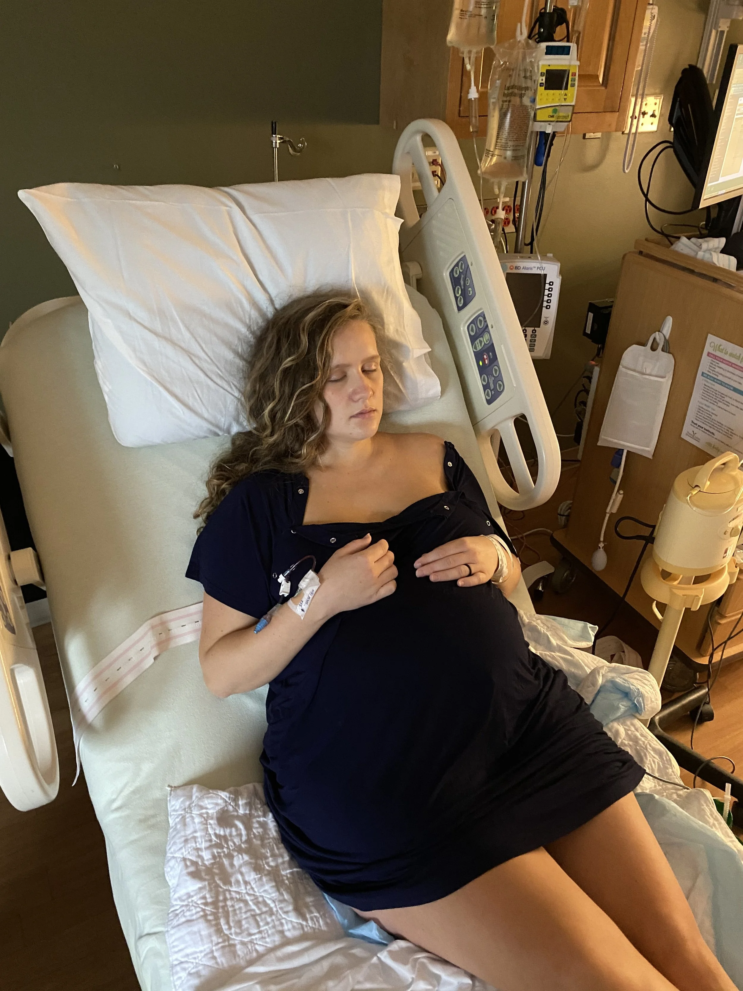 Exhausted but peaceful pregnant mother in her hospital gown laying on the hospital bed after an epidural.