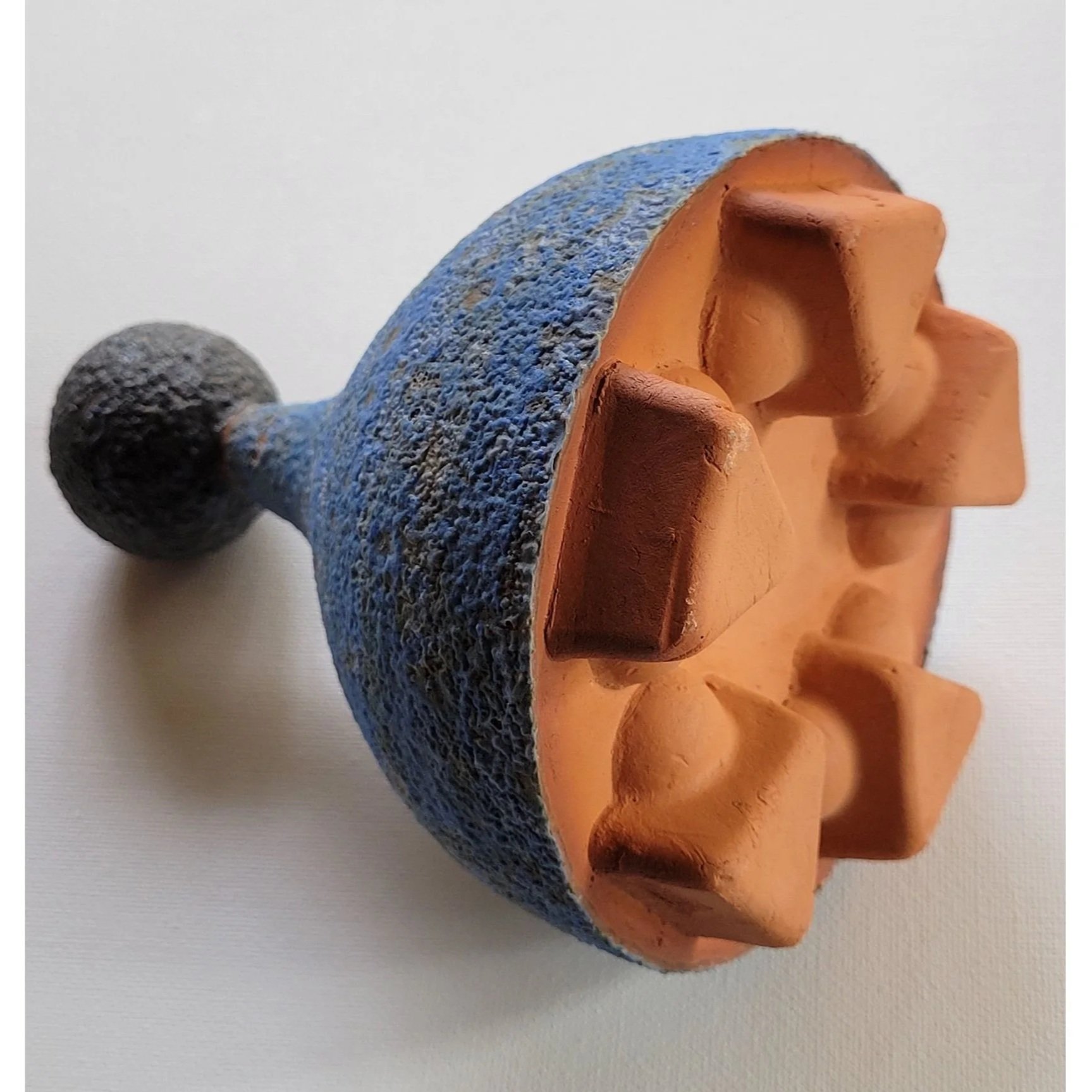 Abstract sculpture of black, blue, and brown in the shape of a rattle.