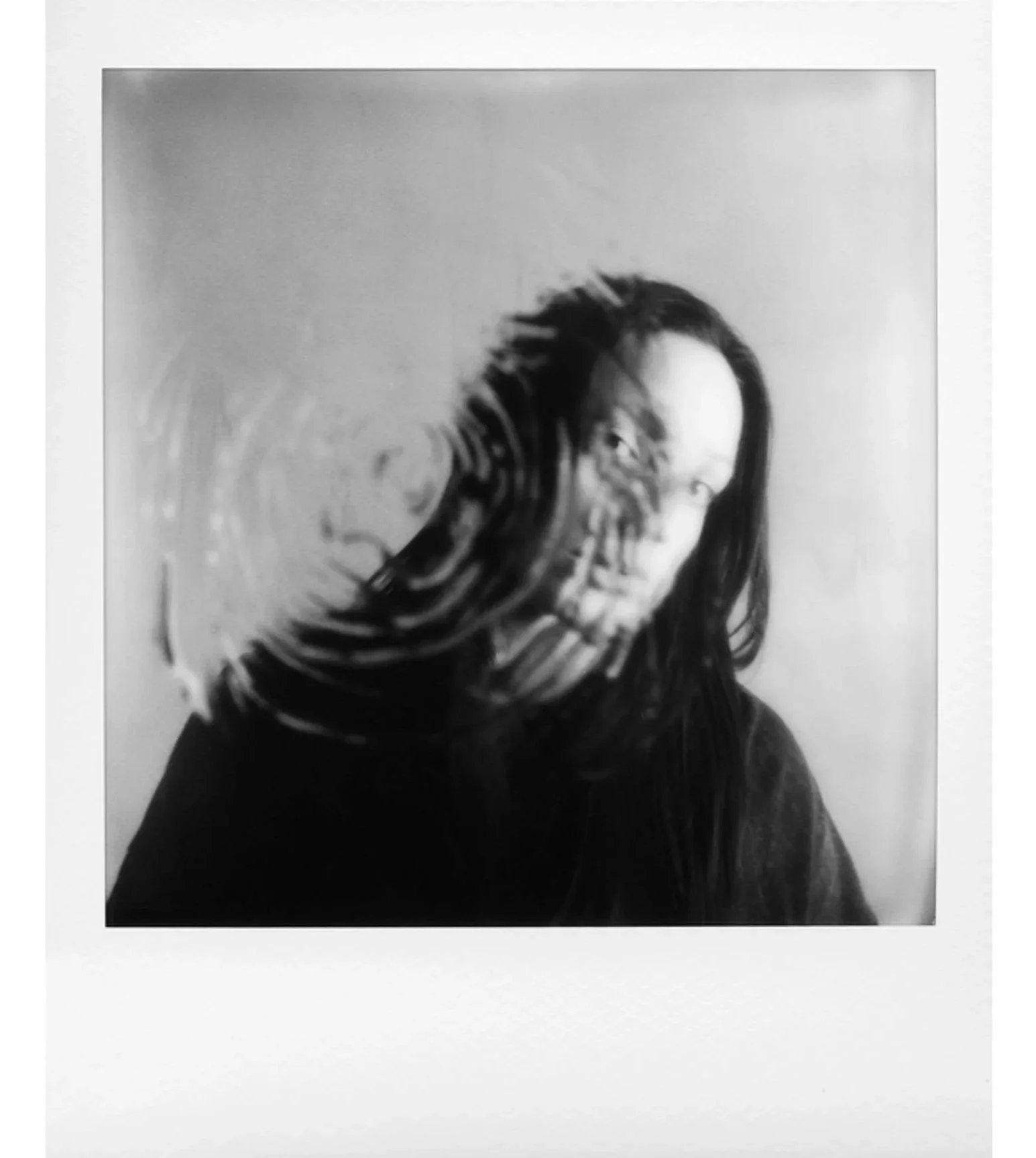 Black and white photo of a person with black hair and black shirt with water droplet on the surface.