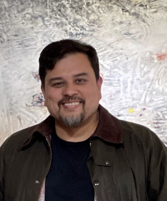 Man smiling in jacket with brown hair.