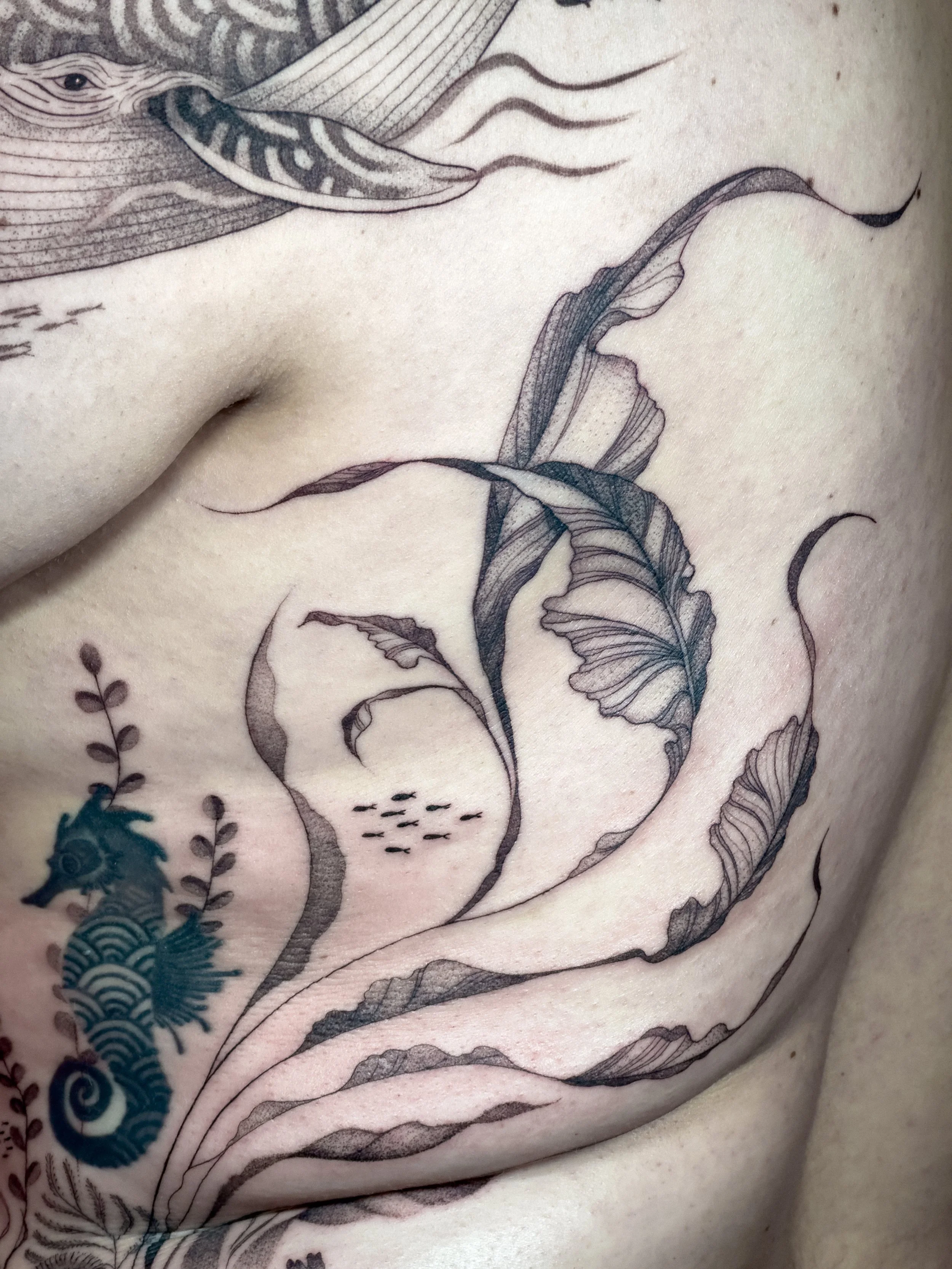 Flowing fine line tattoo inspired by marine life, featuring a whale, organic lines, and botanical ocean elements. Designed to move naturally with the body, creating a soft and cohesive composition across the back and side.

Custom tattoo by Lis Roldá