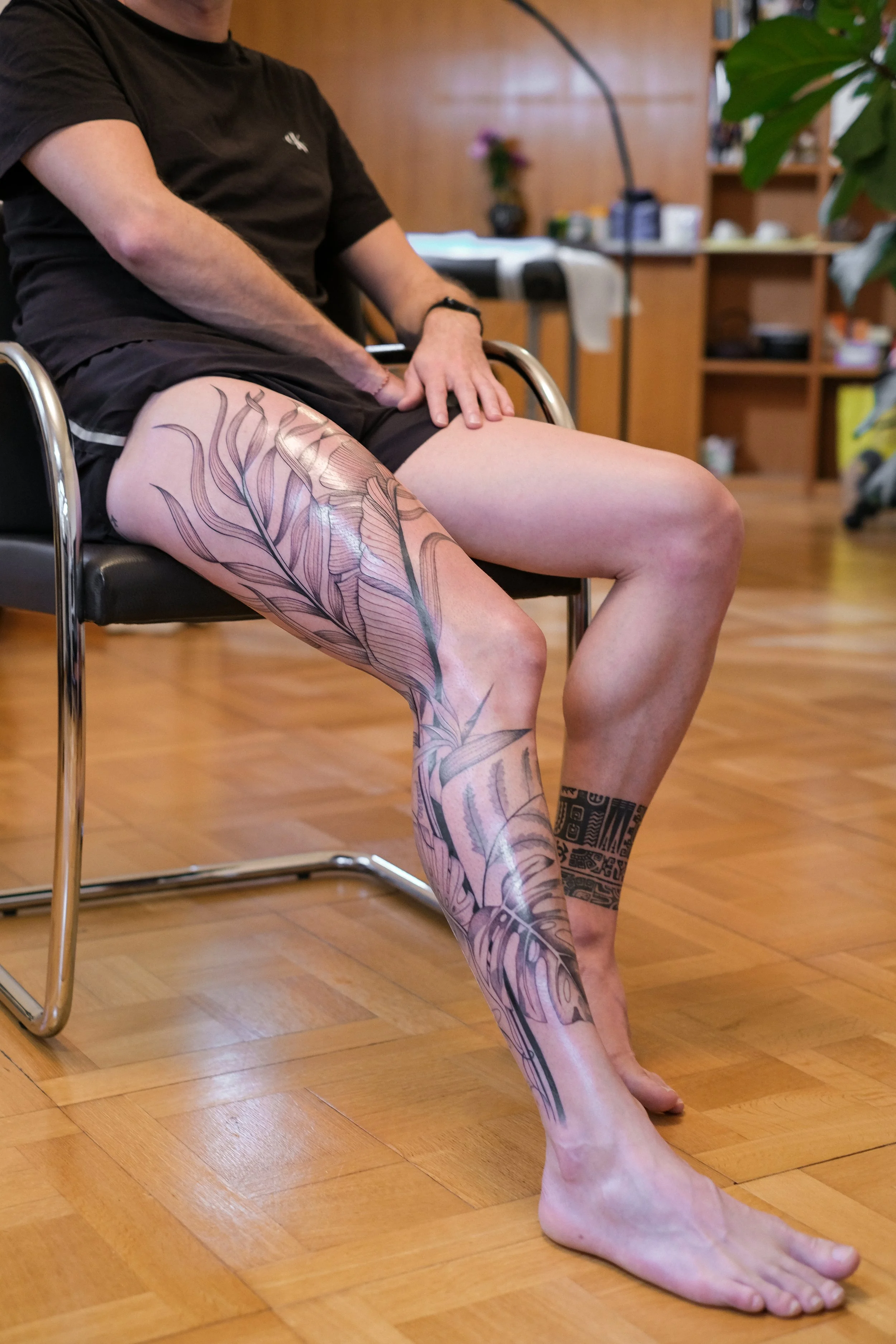 Freehand botanical leg tattoo by Lis Roldan, featuring tropical flowers and plants, custom-designed to follow the natural movement and anatomy of the leg, creating a fluid and harmonious composition.