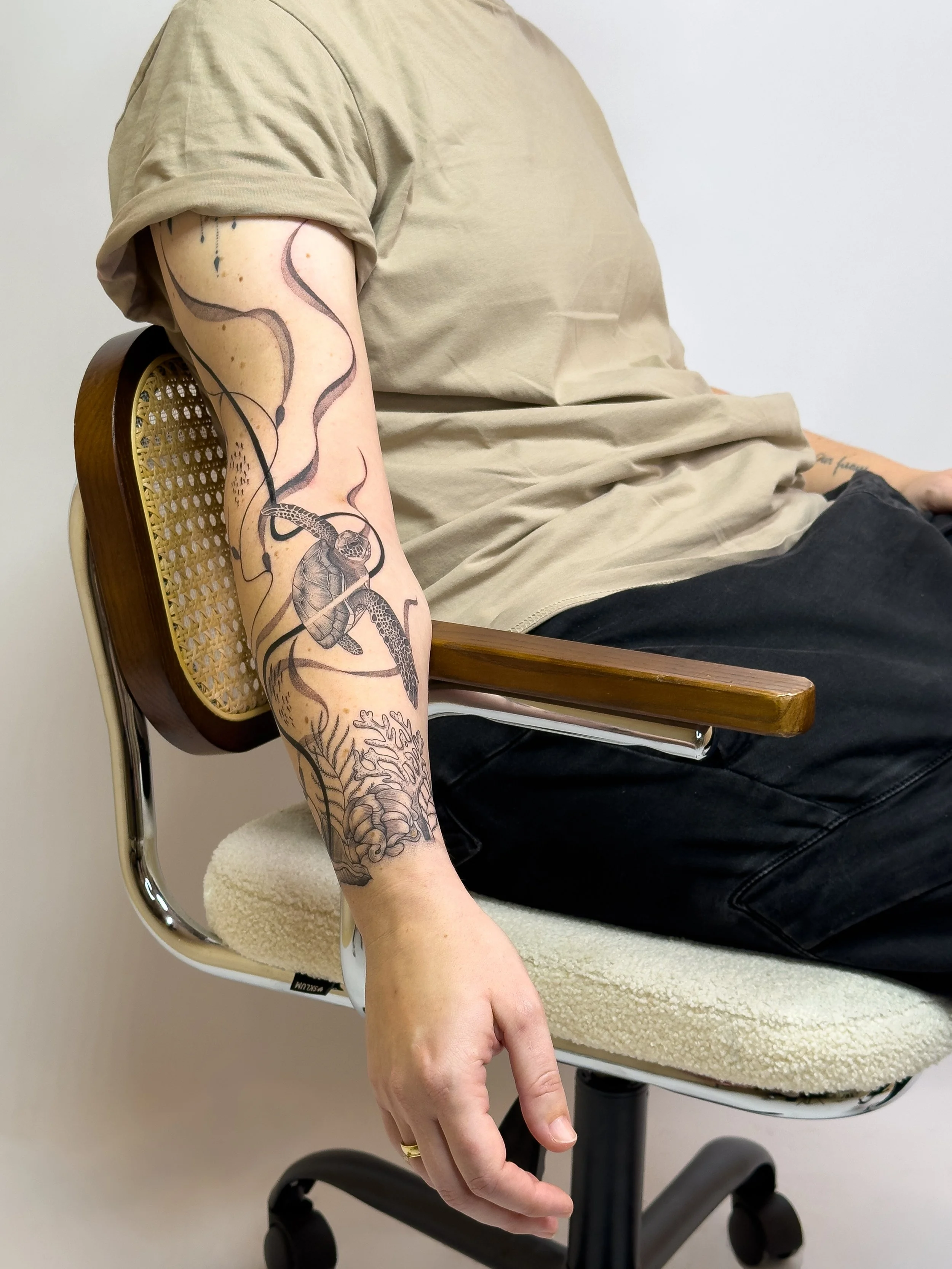 Sea-inspired arm tattoo featuring flowing freehand lines, botanical elements, and a sea turtle, tattooed by Lis Roldan over two sessions. This custom piece was designed to follow the natural shapes and movement of the arm, creating a harmonious and o