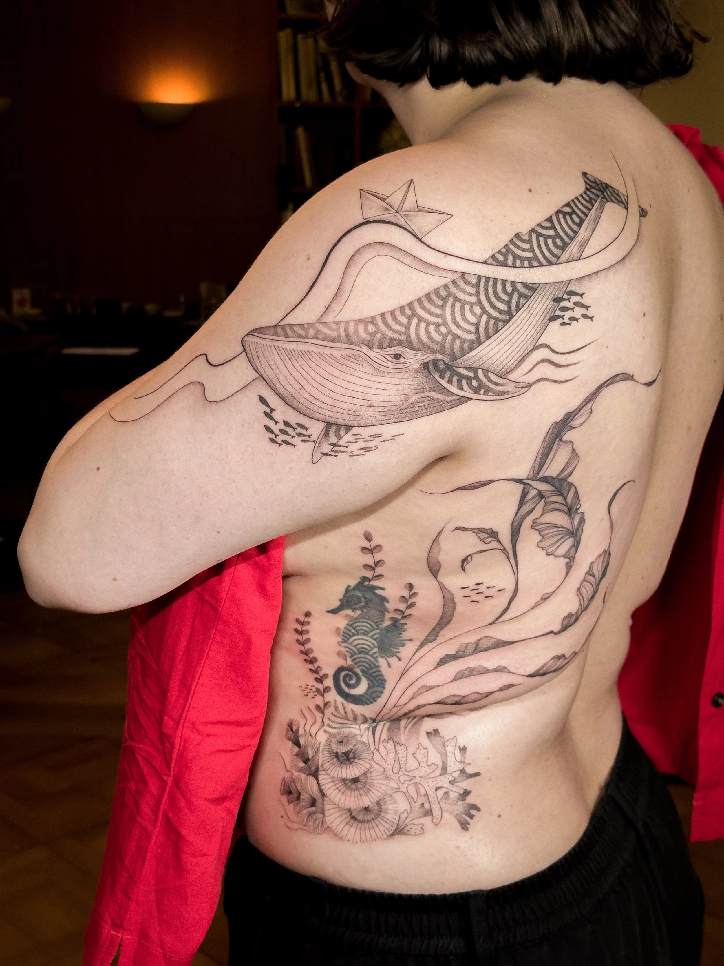 Flowing fine line tattoo inspired by marine life, featuring a whale, organic lines, and botanical ocean elements. Designed to move naturally with the body, creating a soft and cohesive composition across the back and side.

Custom tattoo by Lis Roldá