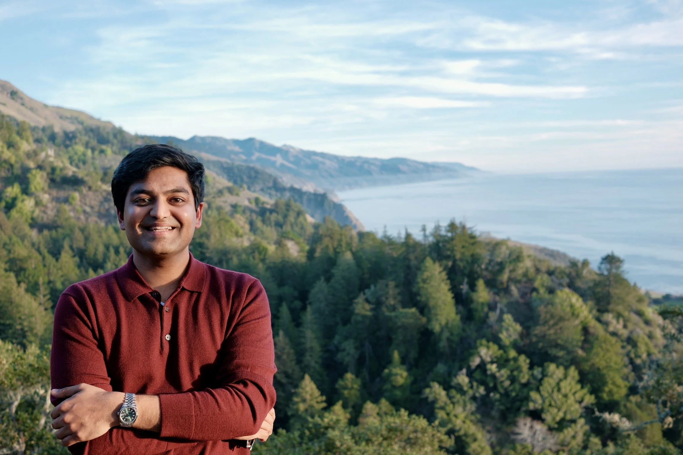 Portrait of Atharva Naik, UX designer, photographed outdoors with a natural landscape backdrop.