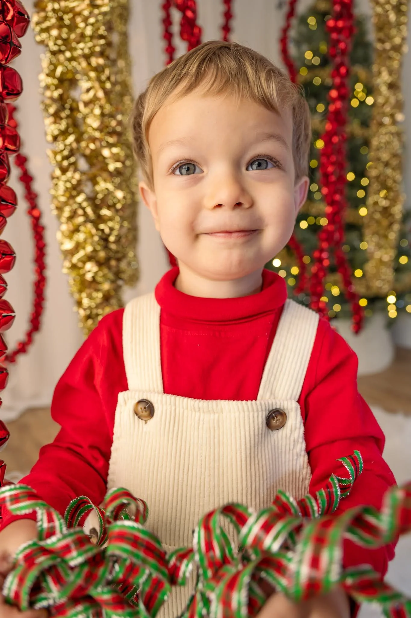 Toggler smiles at the camera, surrounded by jingle bells and gold garlands for a Christmas Mini Session in Wausau WI.