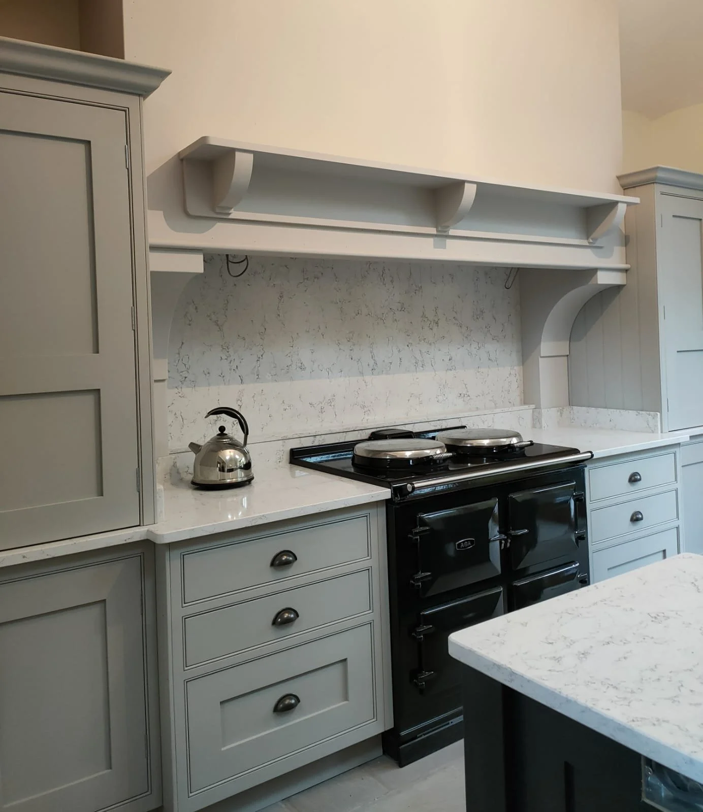 Kitchen with gray cabinets, a black stove, a metal kettle, and a marble countertop.