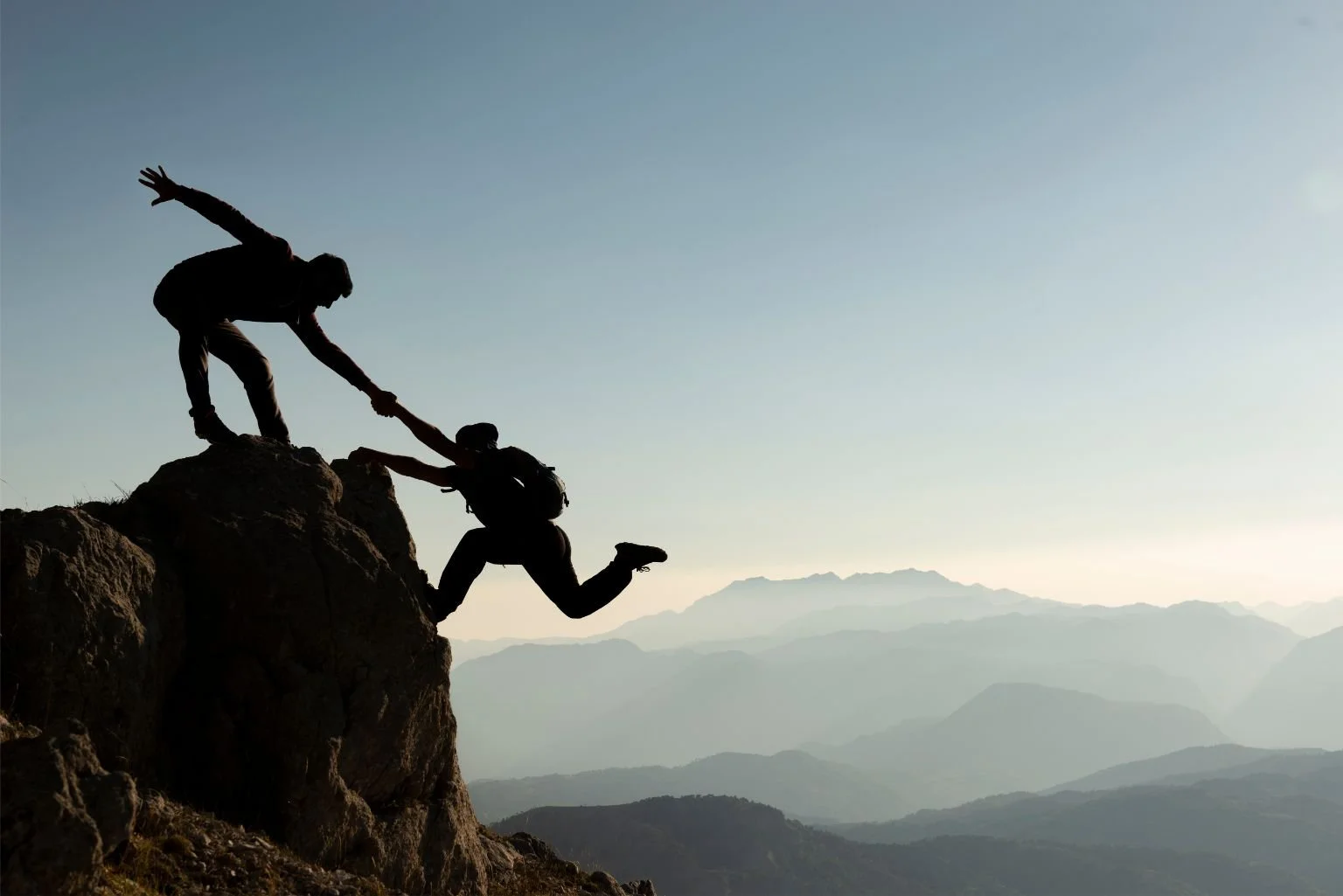 Frontline employees supporting each other whilst on a mountain hike together.