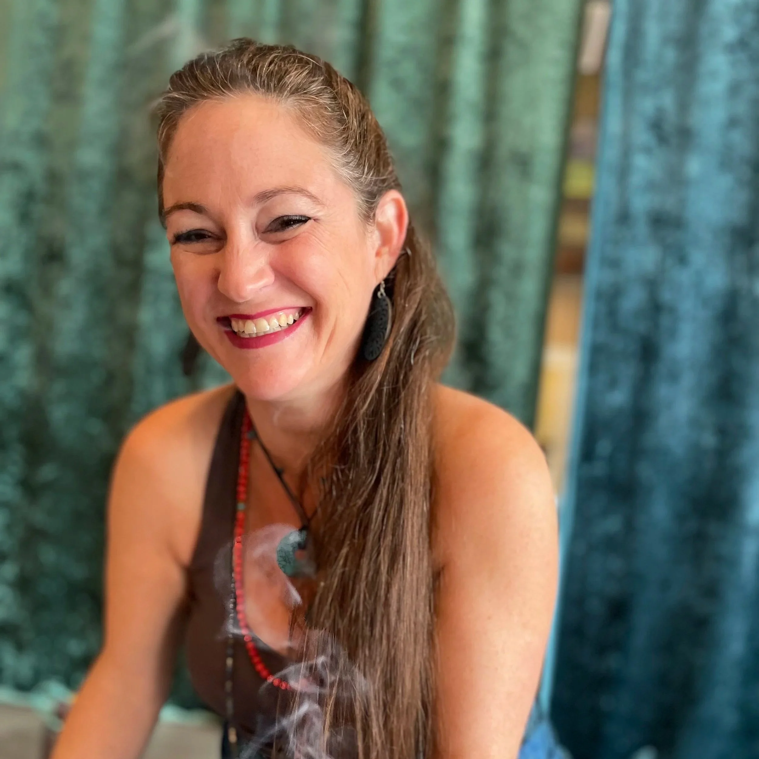 Angela smiling with burning sage. 