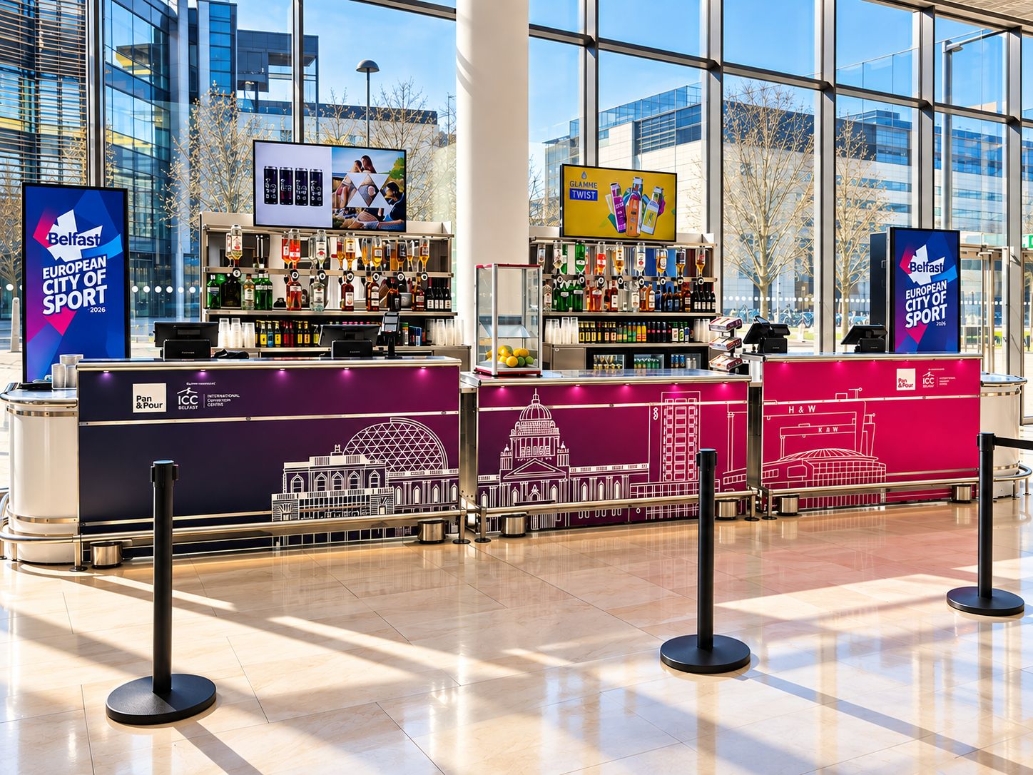 A modern bar inside a building with large glass windows, showcasing bottles of alcohol, digital screens, and promotional signage.