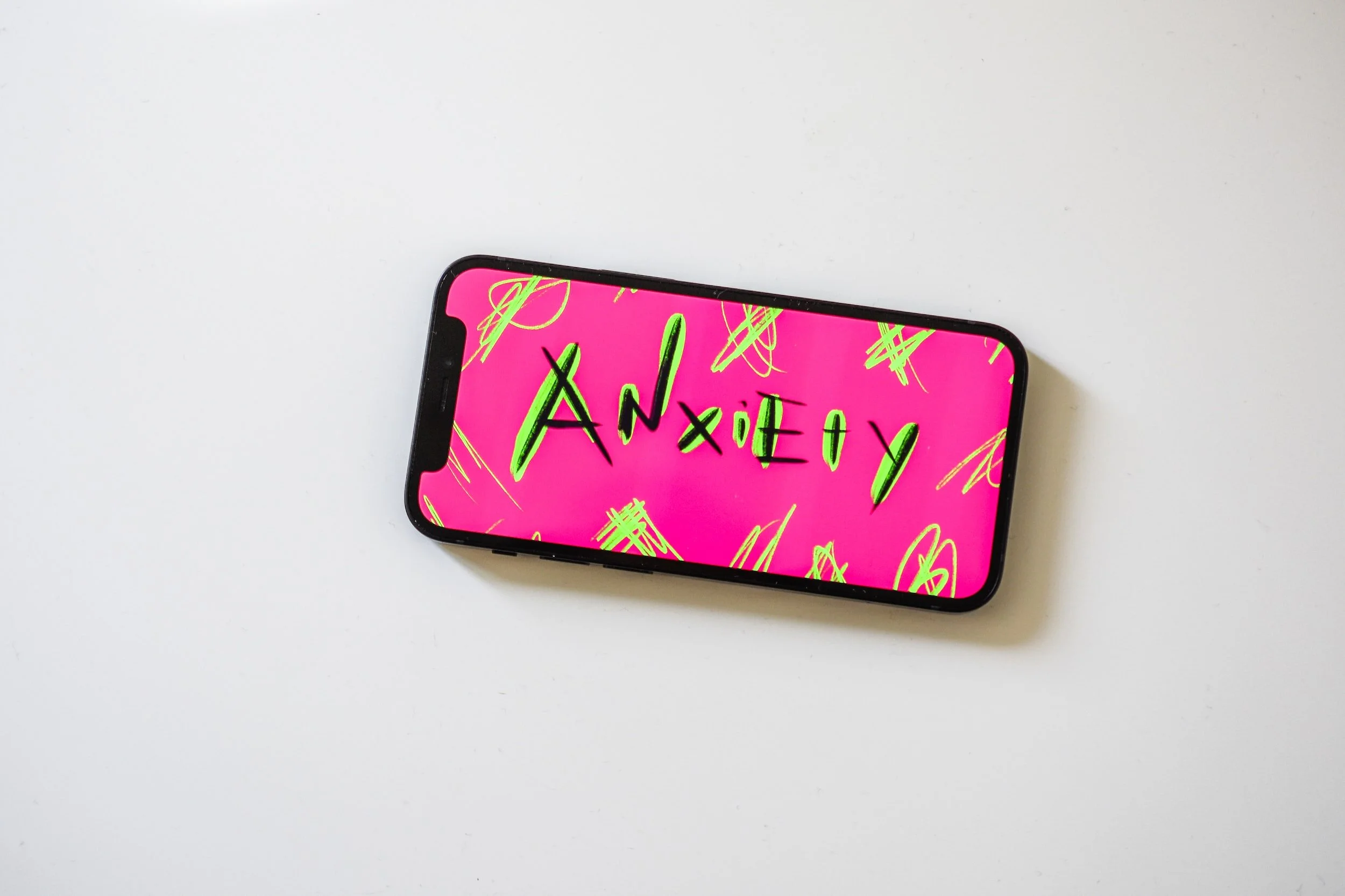 Pink mobile phone case with the word 'anxiety' handwritten on it