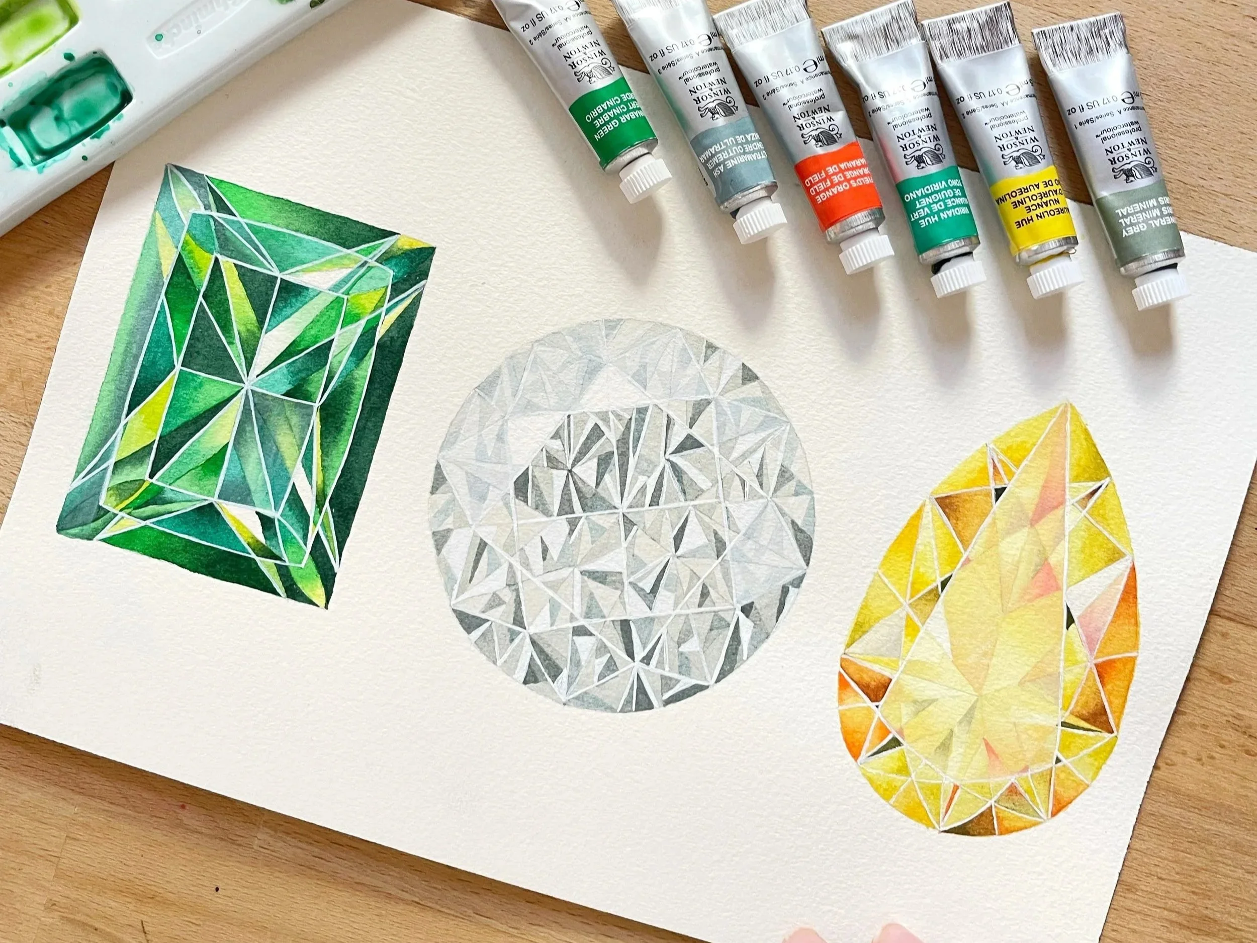 Three watercolor gemstones, one yellow diamond, one clear diamond, one green emerald