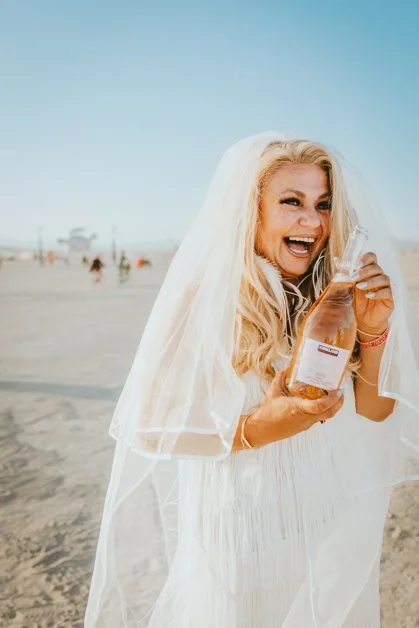Burning Man wedding. Bride holding a Kirkland bottle of Champagne.