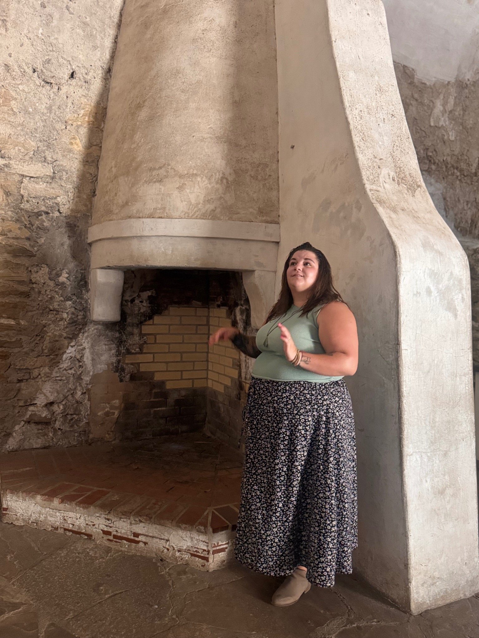 Kate beside a tall stone fireplace at Mission San José in San Antonio, Texas.
