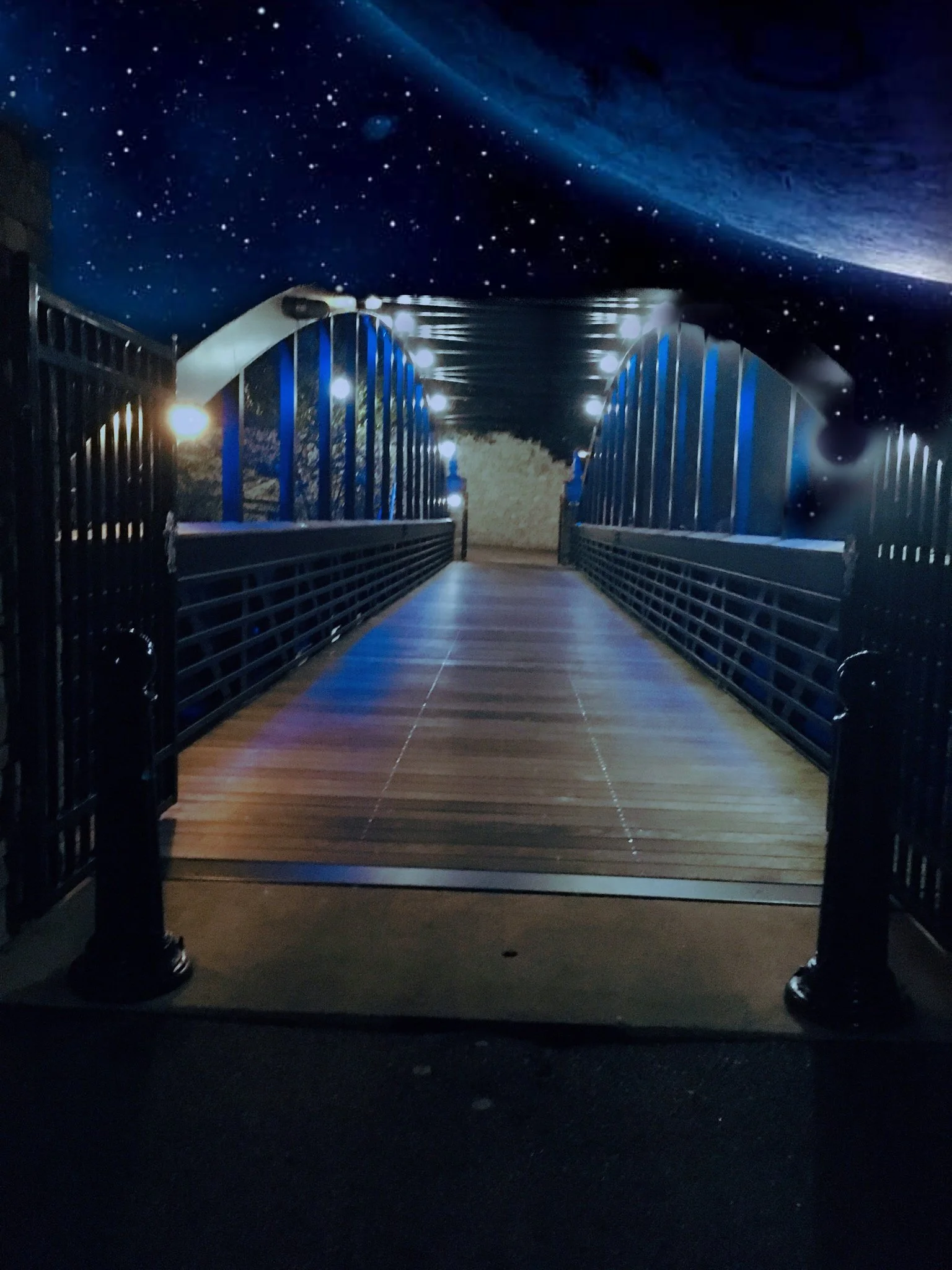 Illuminated bridge at night with space-themed sky