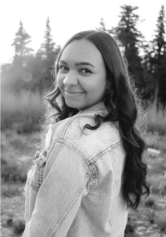 Interior designer Ronniesha Rivera with Vetted By Design, a resource platform for interior designers, smiling and looking over her shoulder, wearing a denim jacket outdoors with trees in the background.