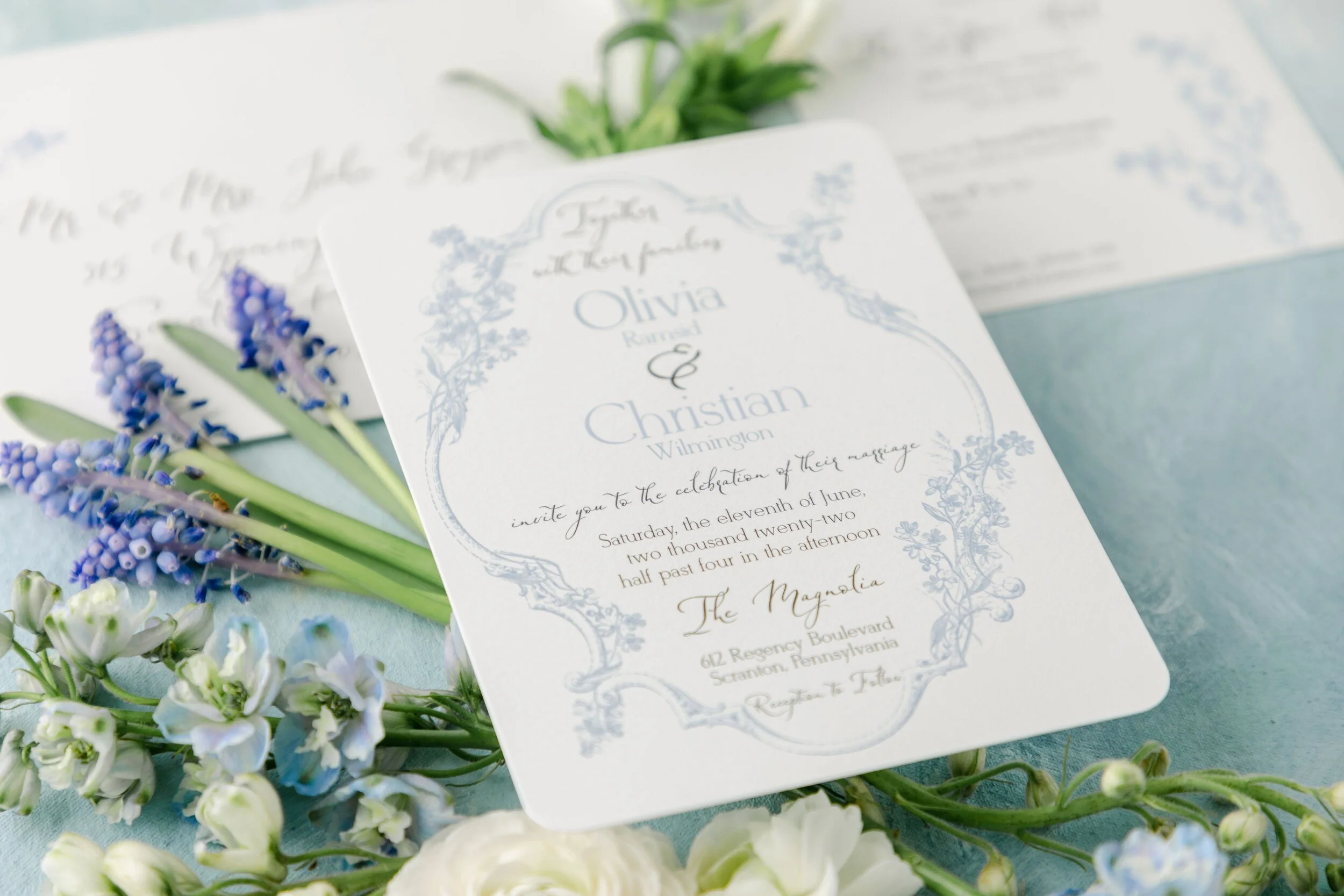 blue regency inspired wedding invitation with floral frames and delicate script.