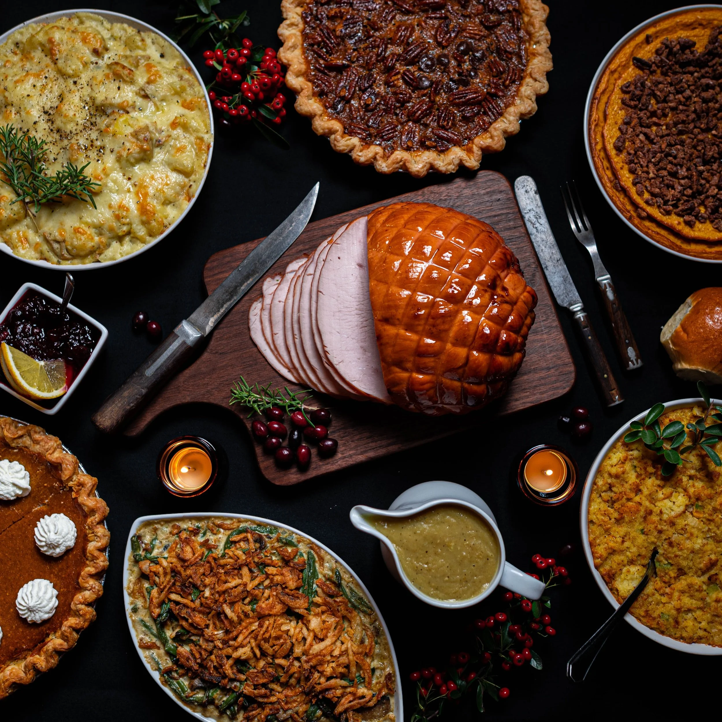 A Thanksgiving feast with various dishes including roasted turkey, stuffing, green bean casserole, mashed potatoes, sweet potato casserole, pumpkin pie, pecan pie, and cranberry sauce, decorated with cranberries and candles.
