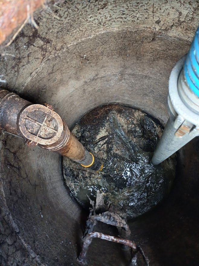 Septic Works staff cleaning a rural septic tank with hose and vaccum