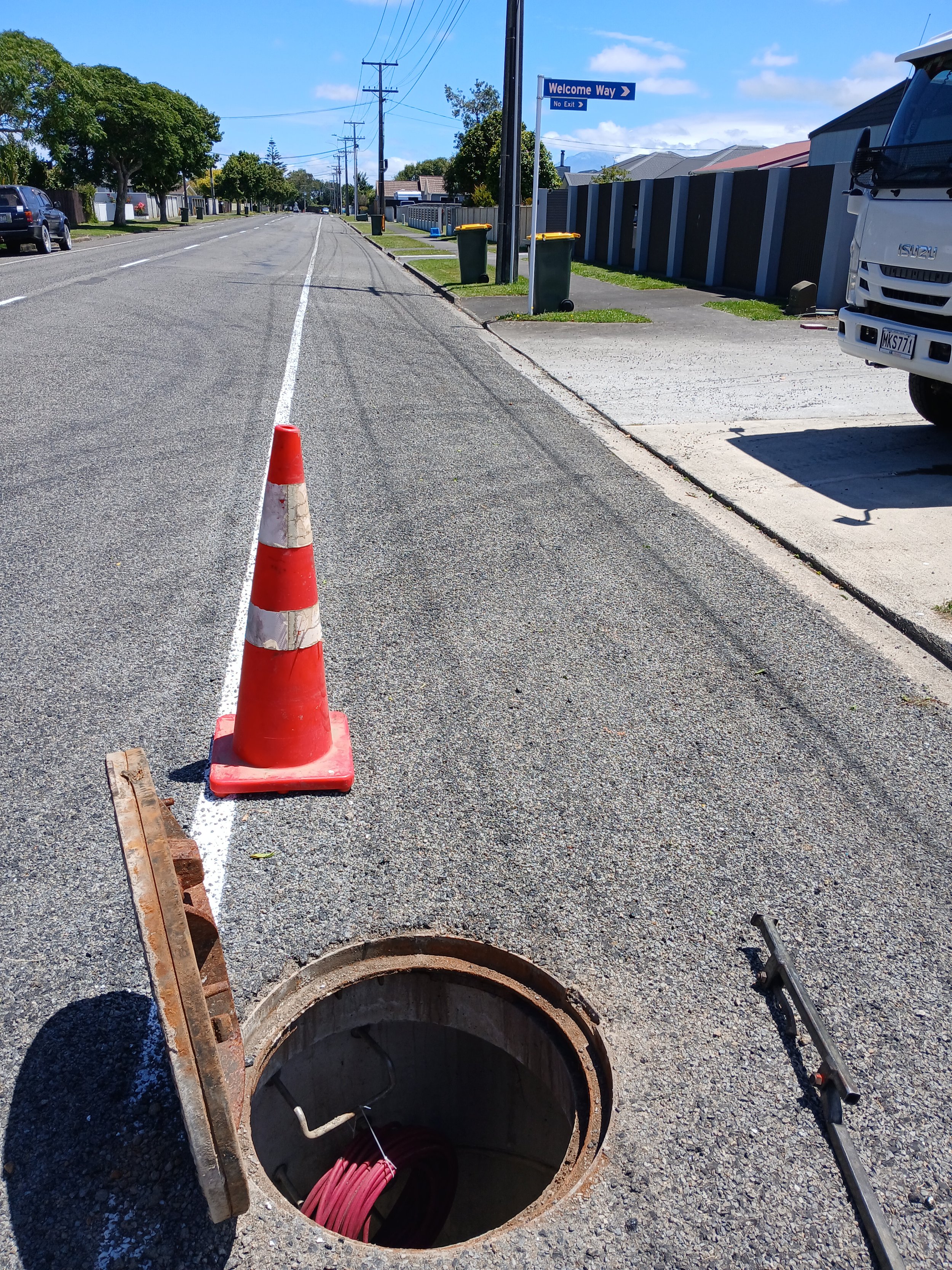 Open septic drains on road with cone