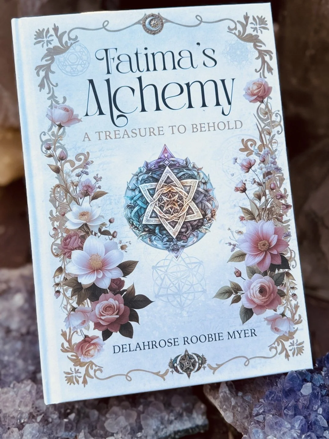 Book cover titled "Fatima's Alchemy: A Treasure to Behold" by Delahrose Roobie Myer, featuring floral illustrations and mystical symbols.
