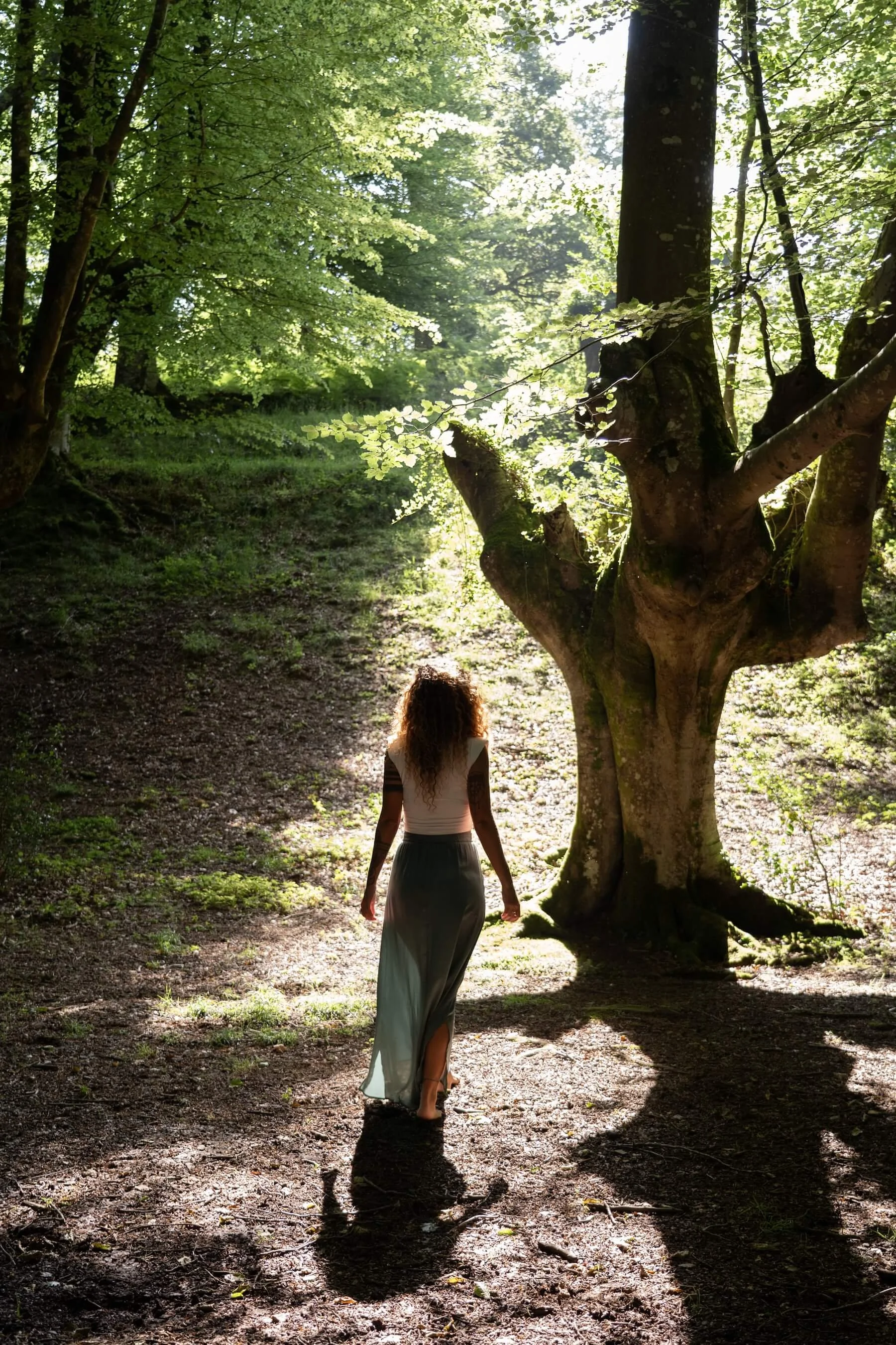 Ana en el bosque, aparece de espaldas caminando entre los árboles.